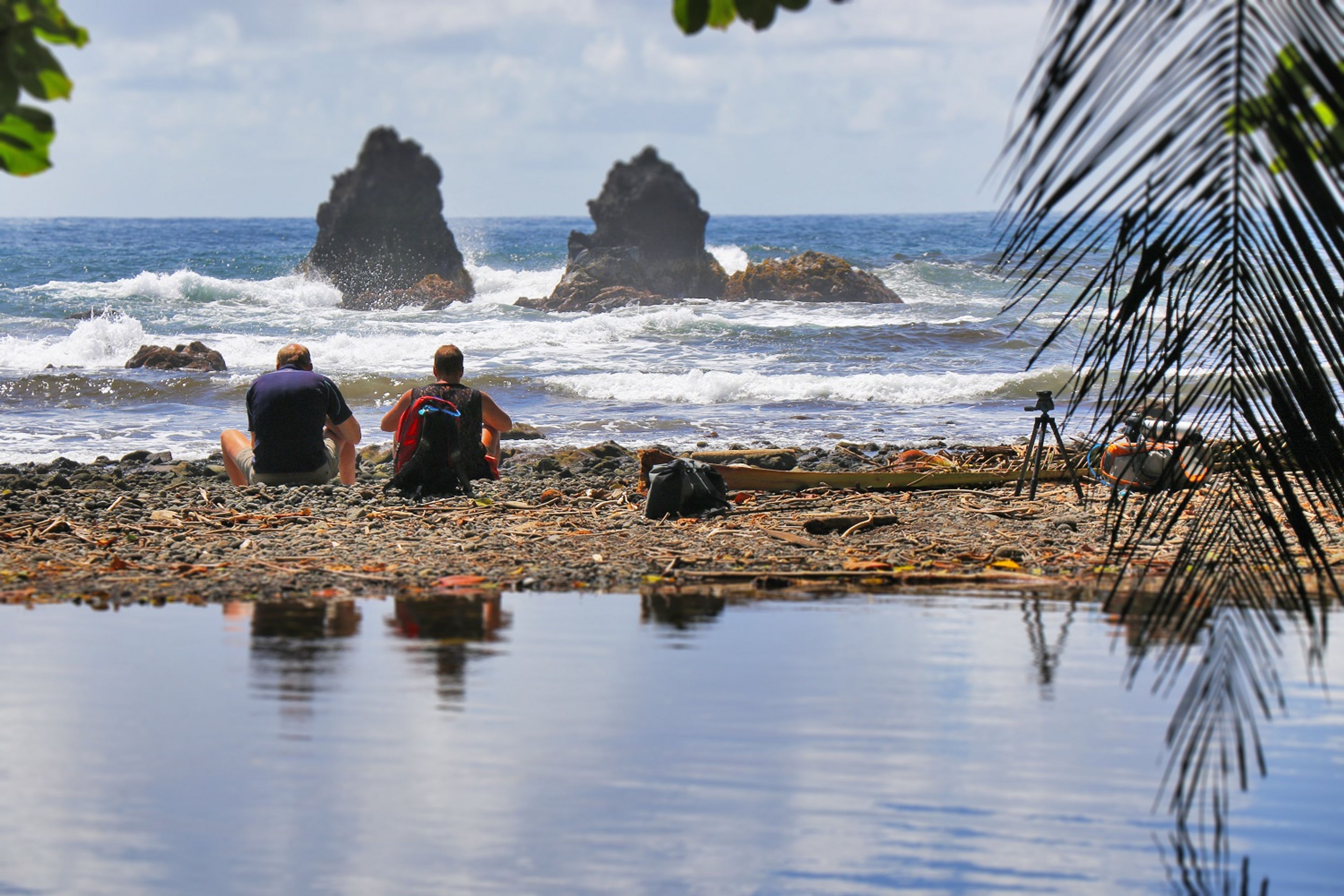 Hikers rest on the shores of Kahaliʻi Bay and enjoy the sea breeze.