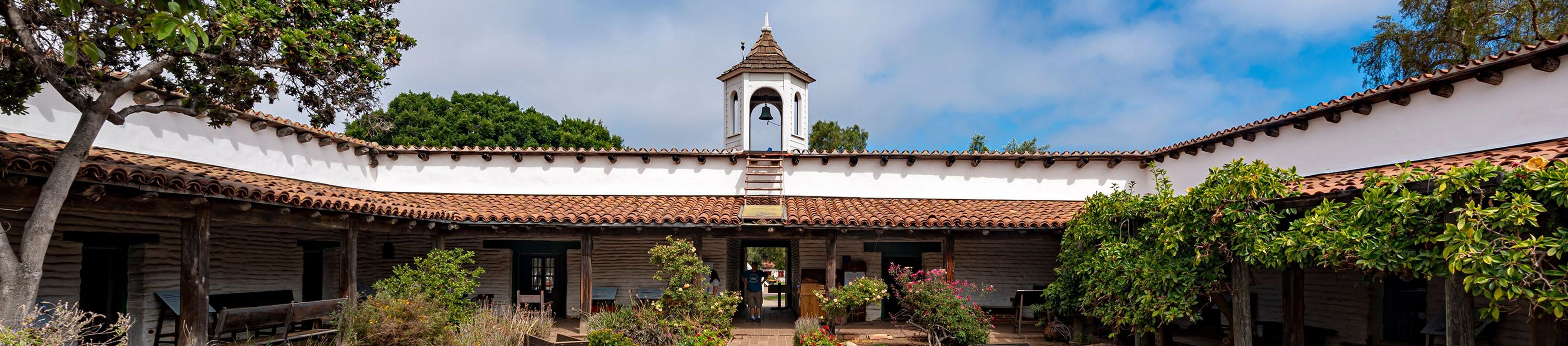 Panoramic photo of La Casa de Estudillo from the interior courtyard toward the Plaza. Has some of the courtyard garden in the foreground.