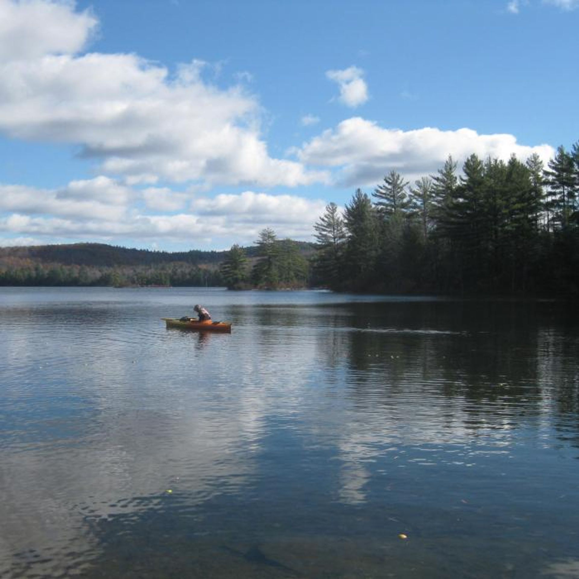 A kayaker paddles in the middle of Grafton Pond.