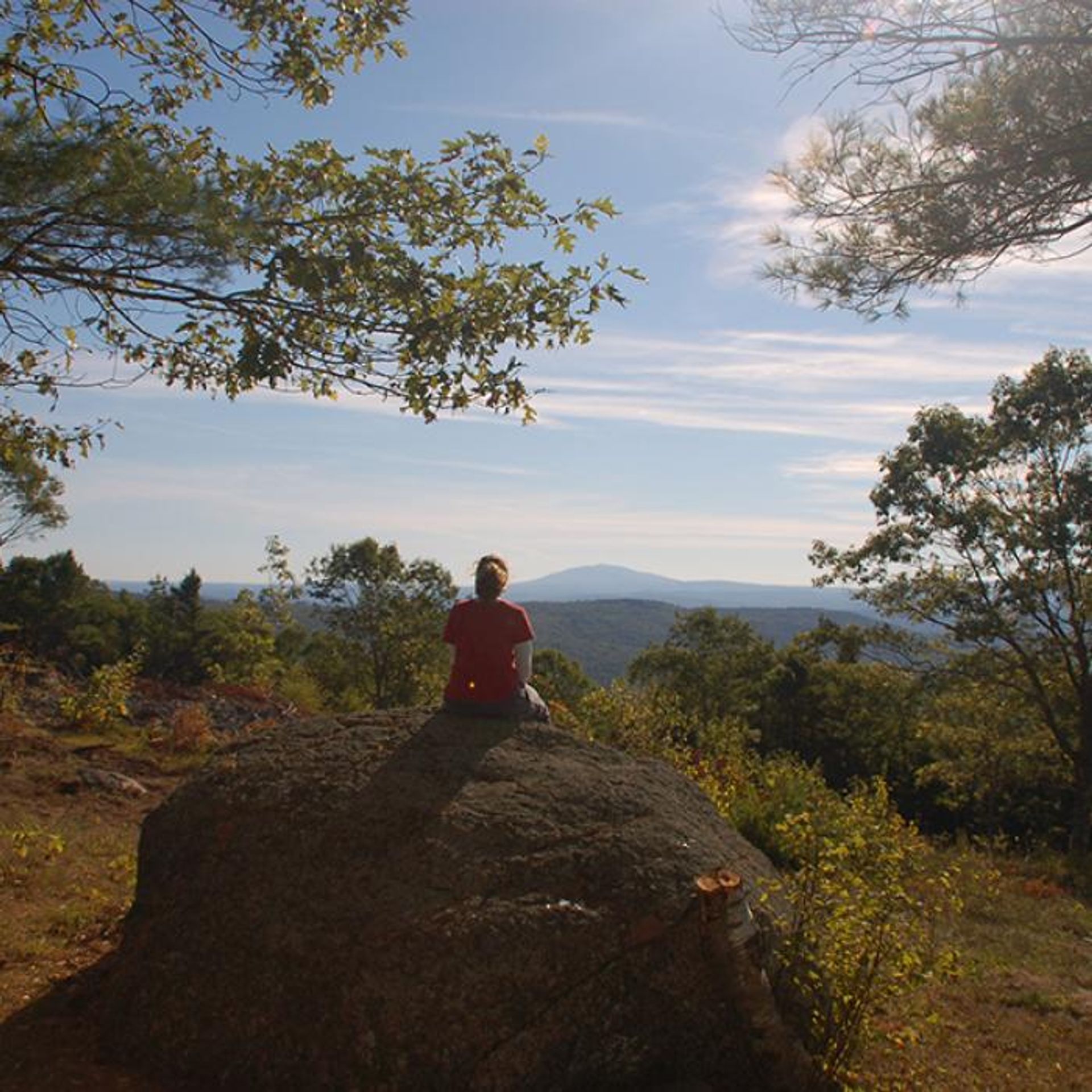 A hiker takes in the view from a boulder at the summit.