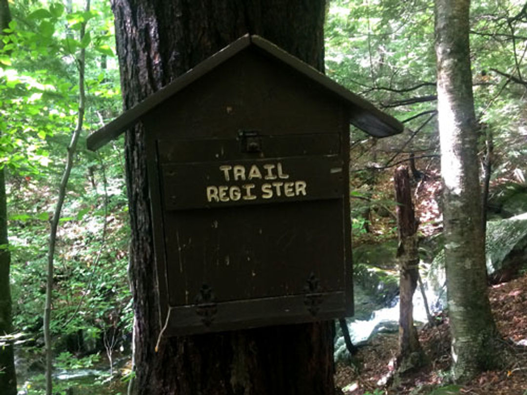 A trail register is housed on a tree.