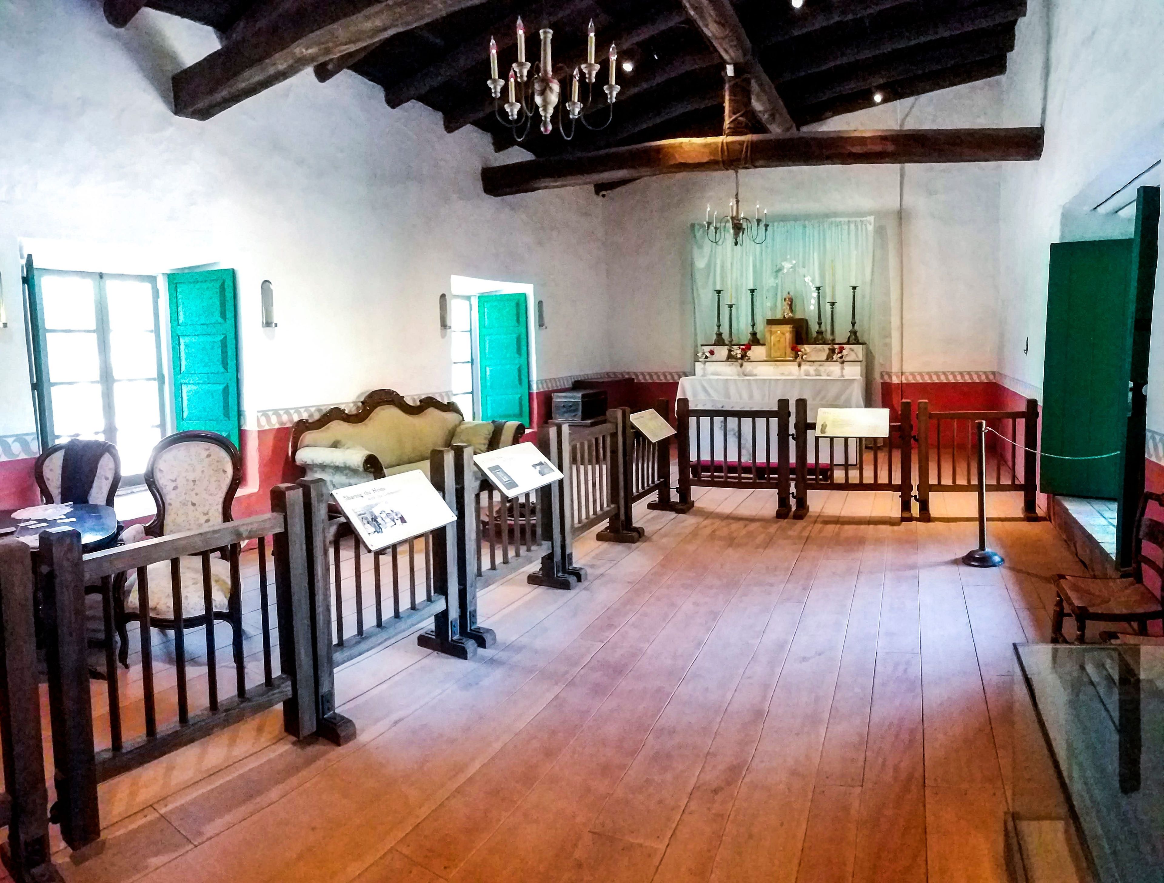 Photo of the Sala in La Casa de Estudillo with an altar at the back and a walkway with interpretive panels on the barriers