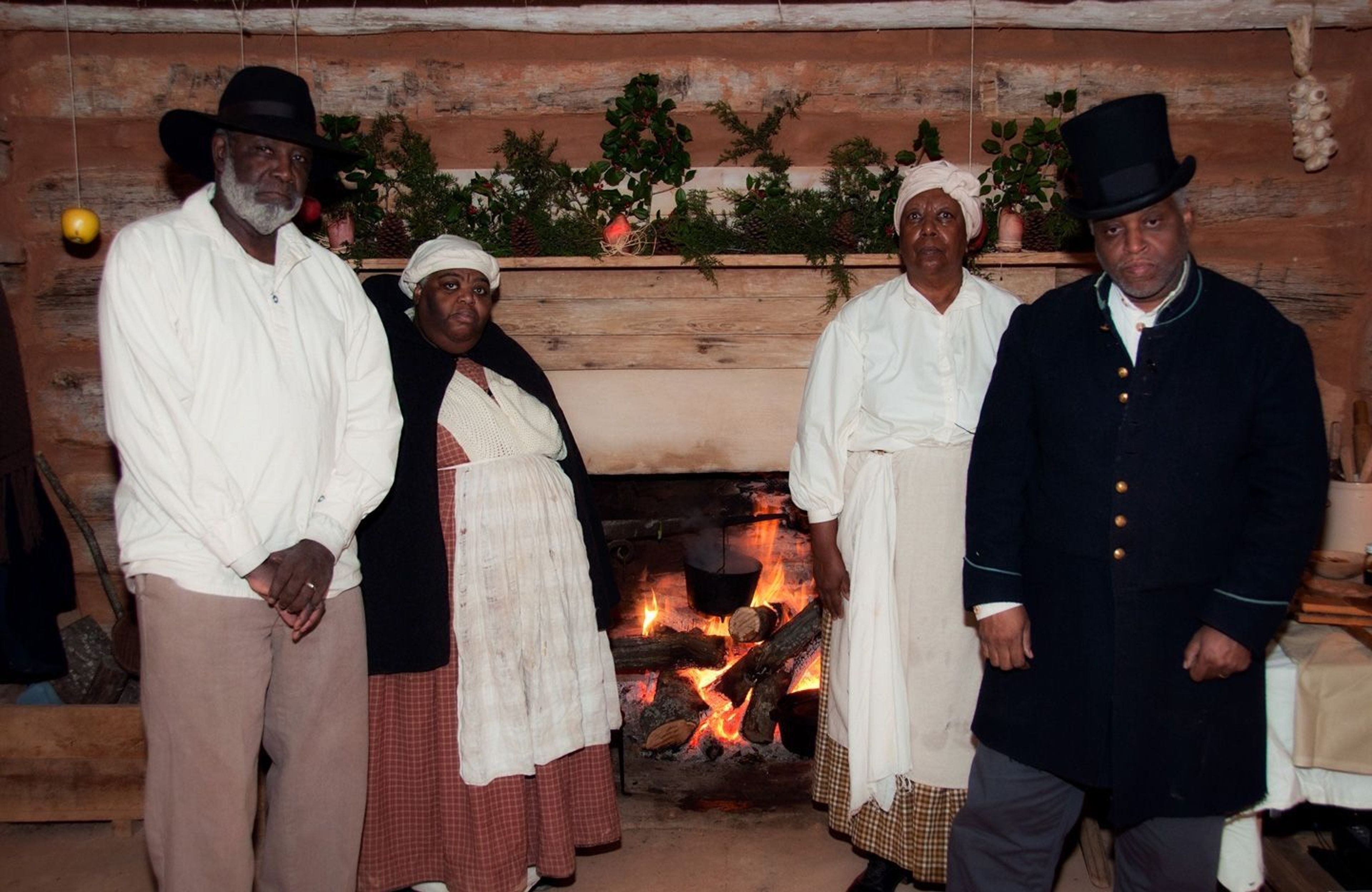 Re-enactors portraying enslaved people in the reconstructed kitchen cabin where Booker T. Washington was born and lived for 9 years.