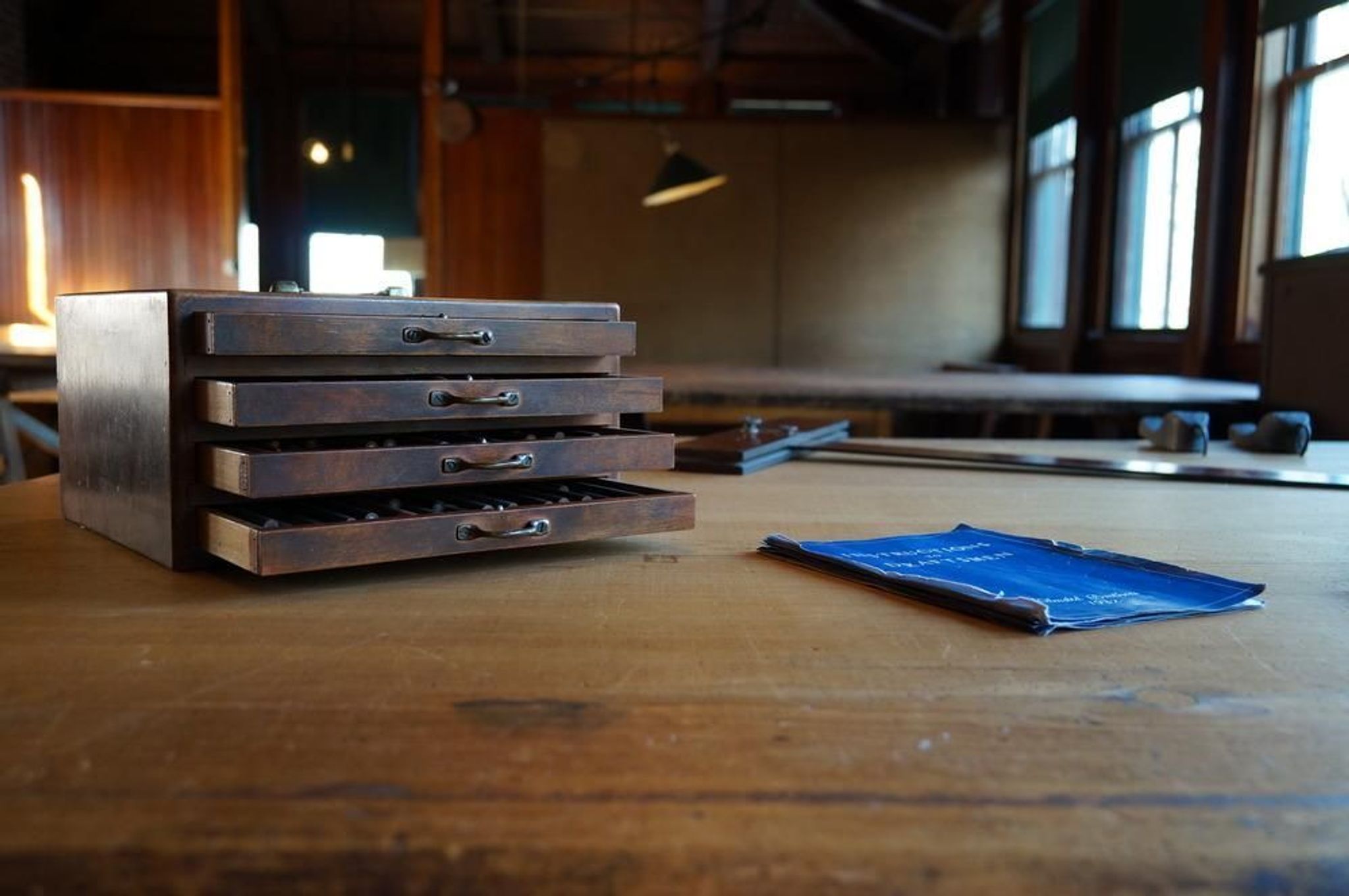 A box of colored pencils and a draftsmen's handbook sit on a table in the drafting room. These materials reflect the period during which Frederick Law Olmsted, Jr. was the senior partner in the Brookline, MA landscape architecture firm.