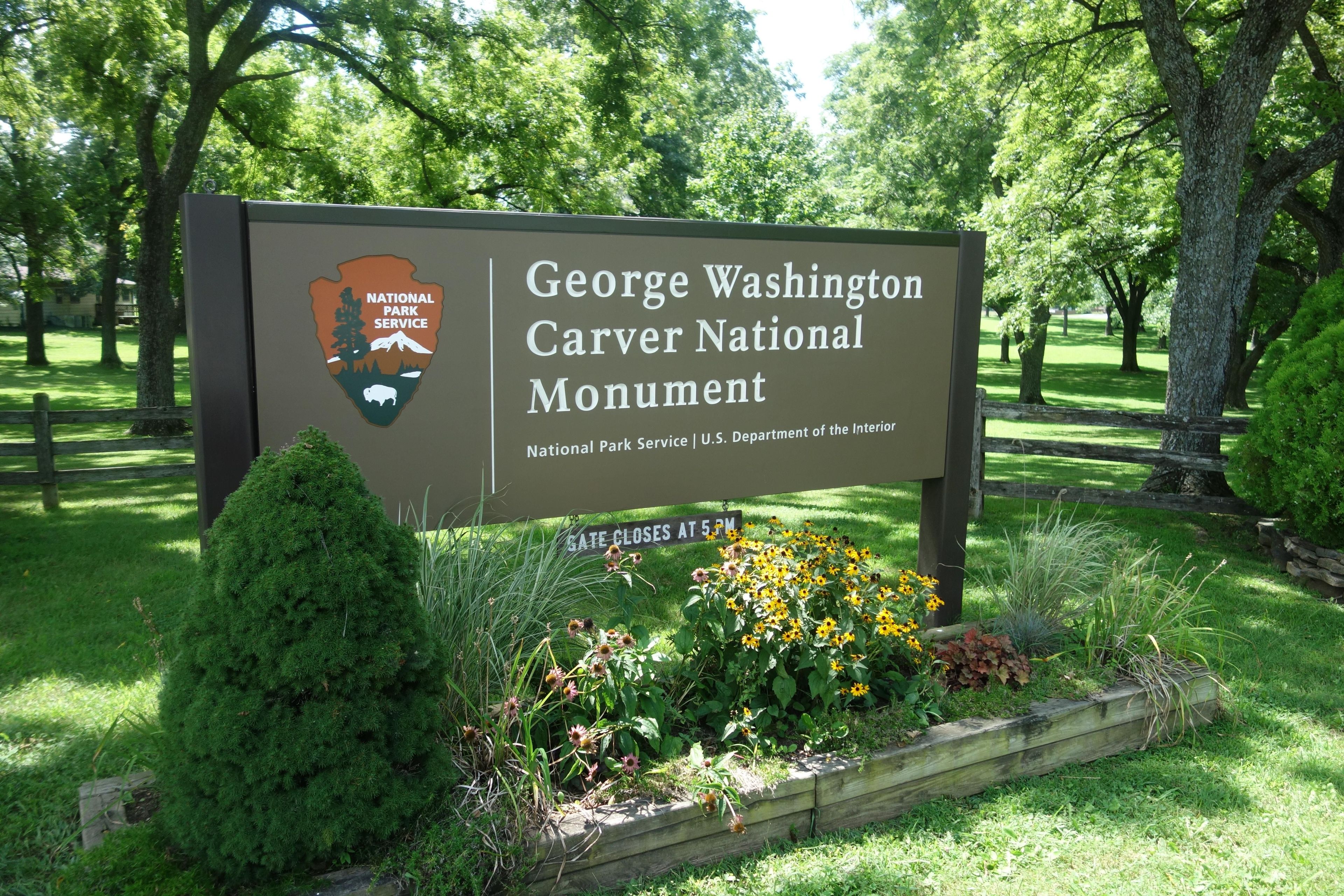 Entrance sign to George Washington Carver NM will wildflower and plants.