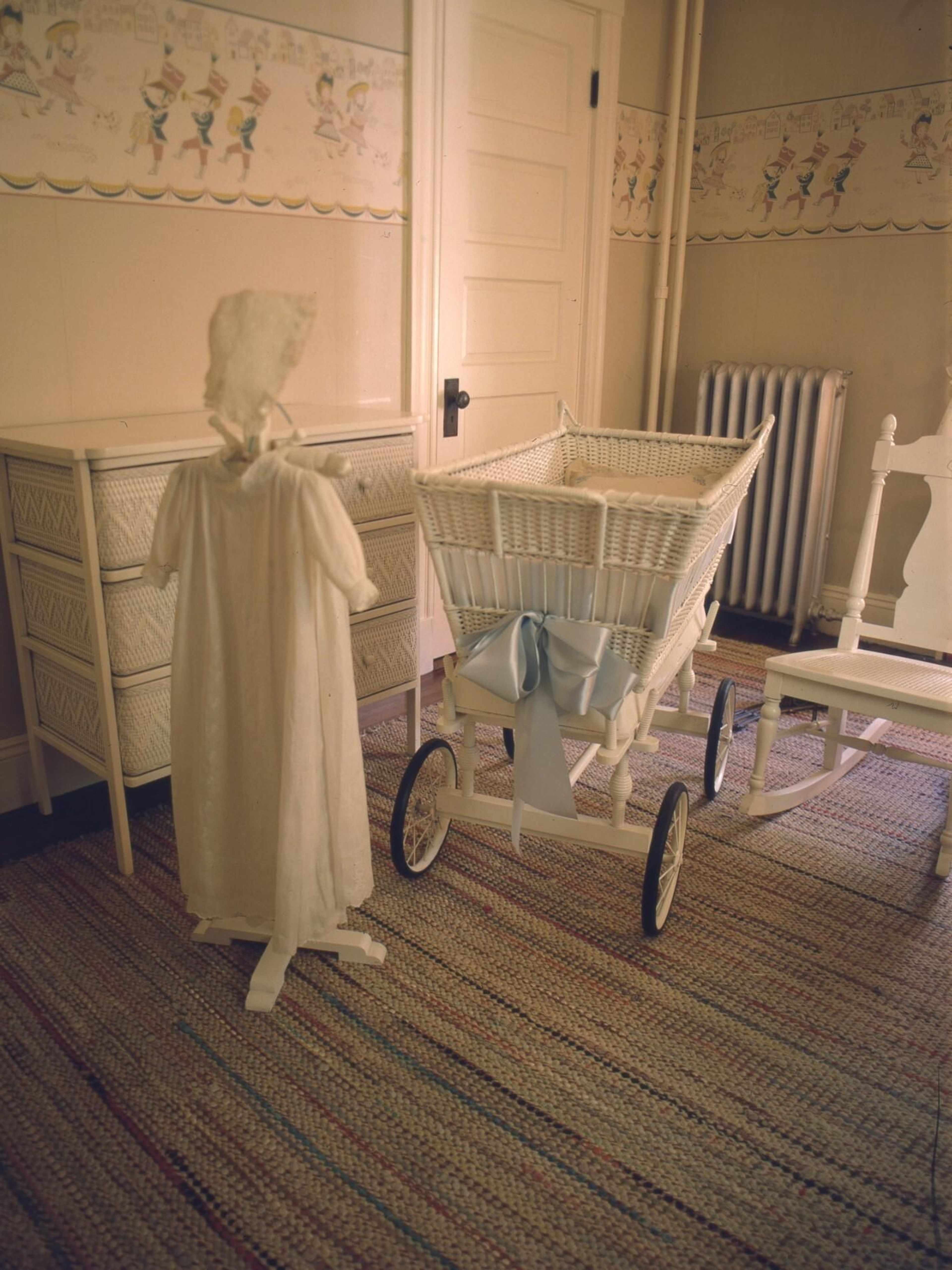 The Kennedy christening gown on a stand next to the bassinet in which all the Kennedy children slept, at the John F. Kennedy National Historic Site.