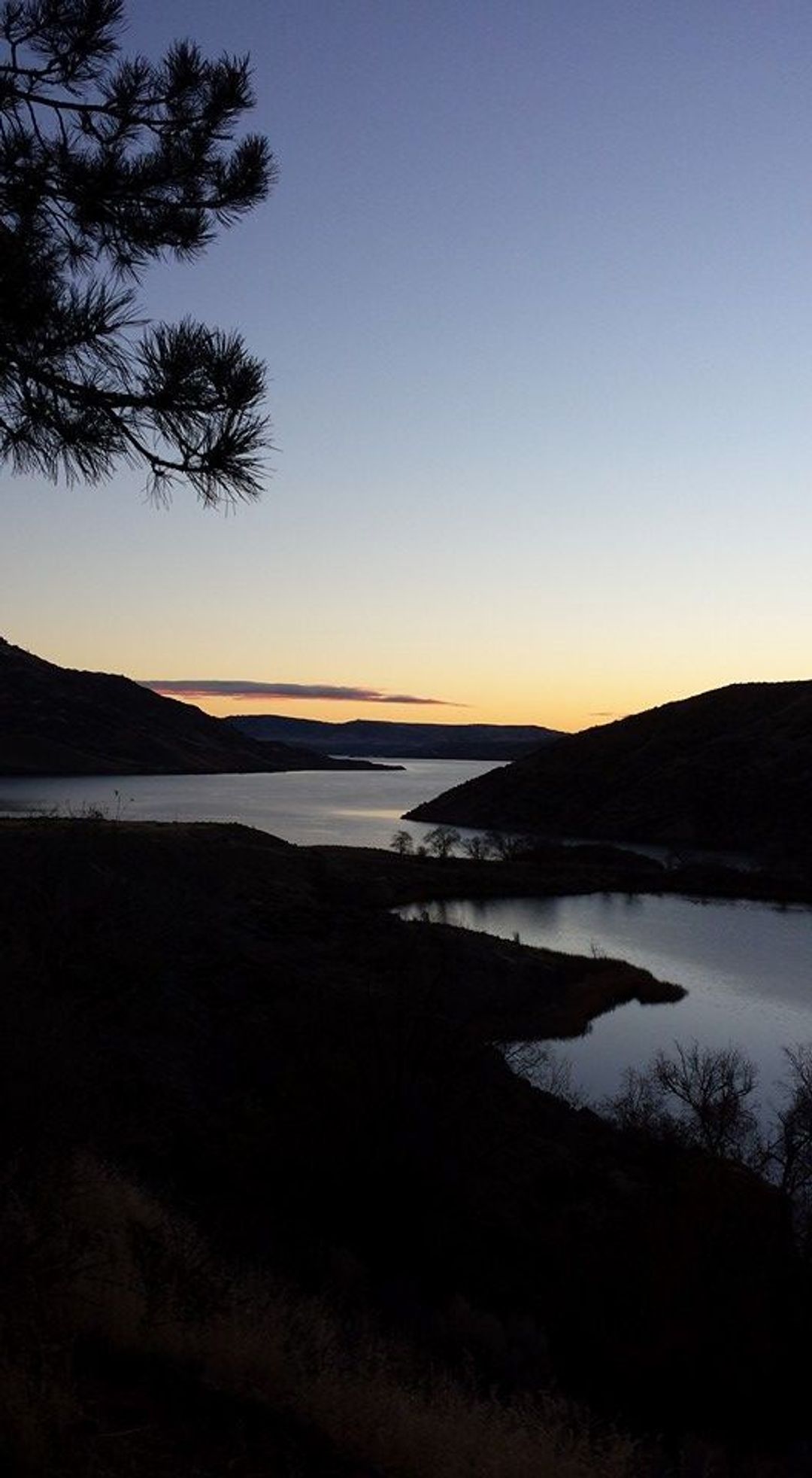 The glow of first light is hitting Lake Roosevelt and Crescent Bay Lake.