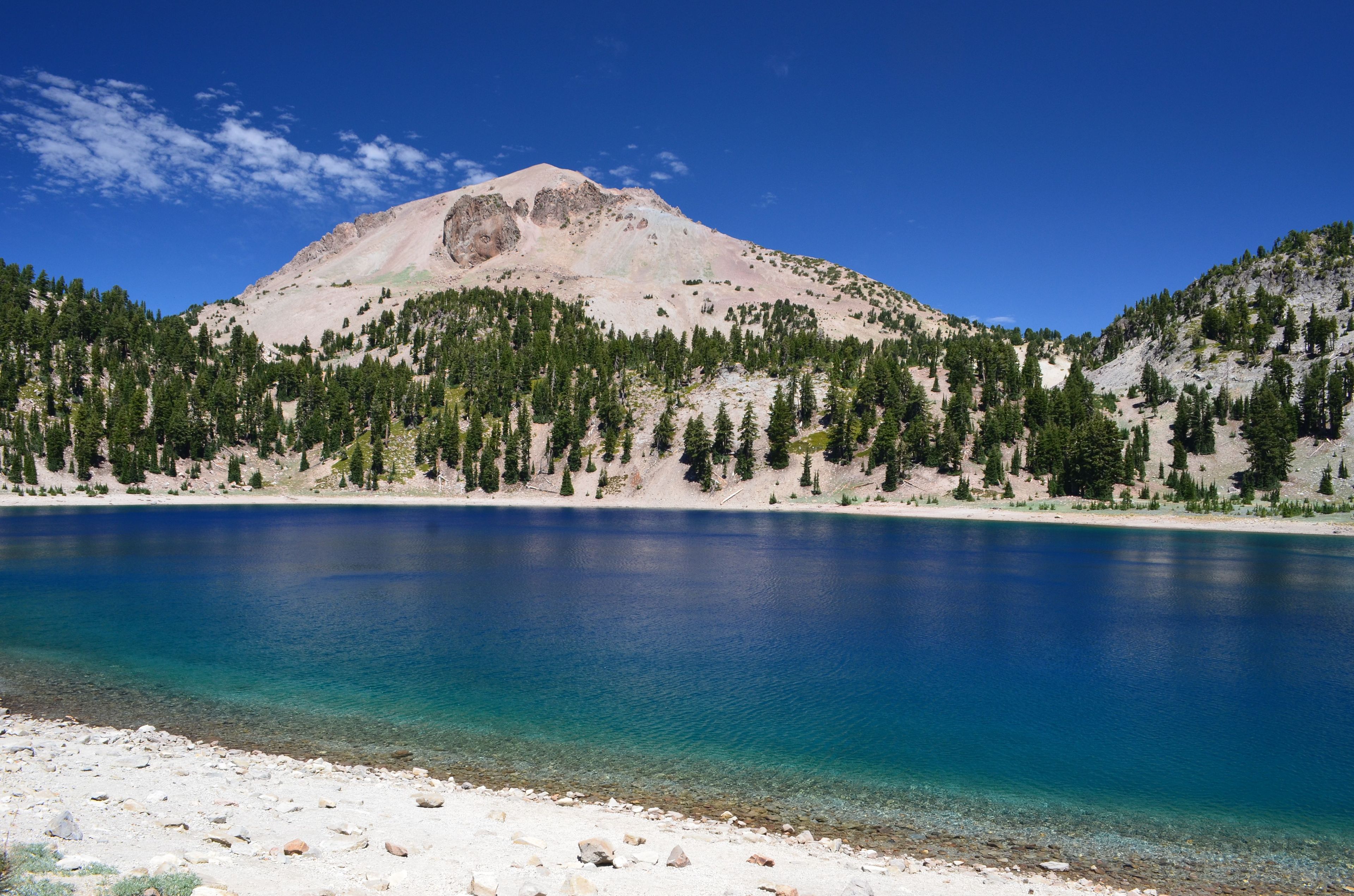 Lassen Peak stands out boldly between the bright blue sky and the sapphire hue of Lake Helen.