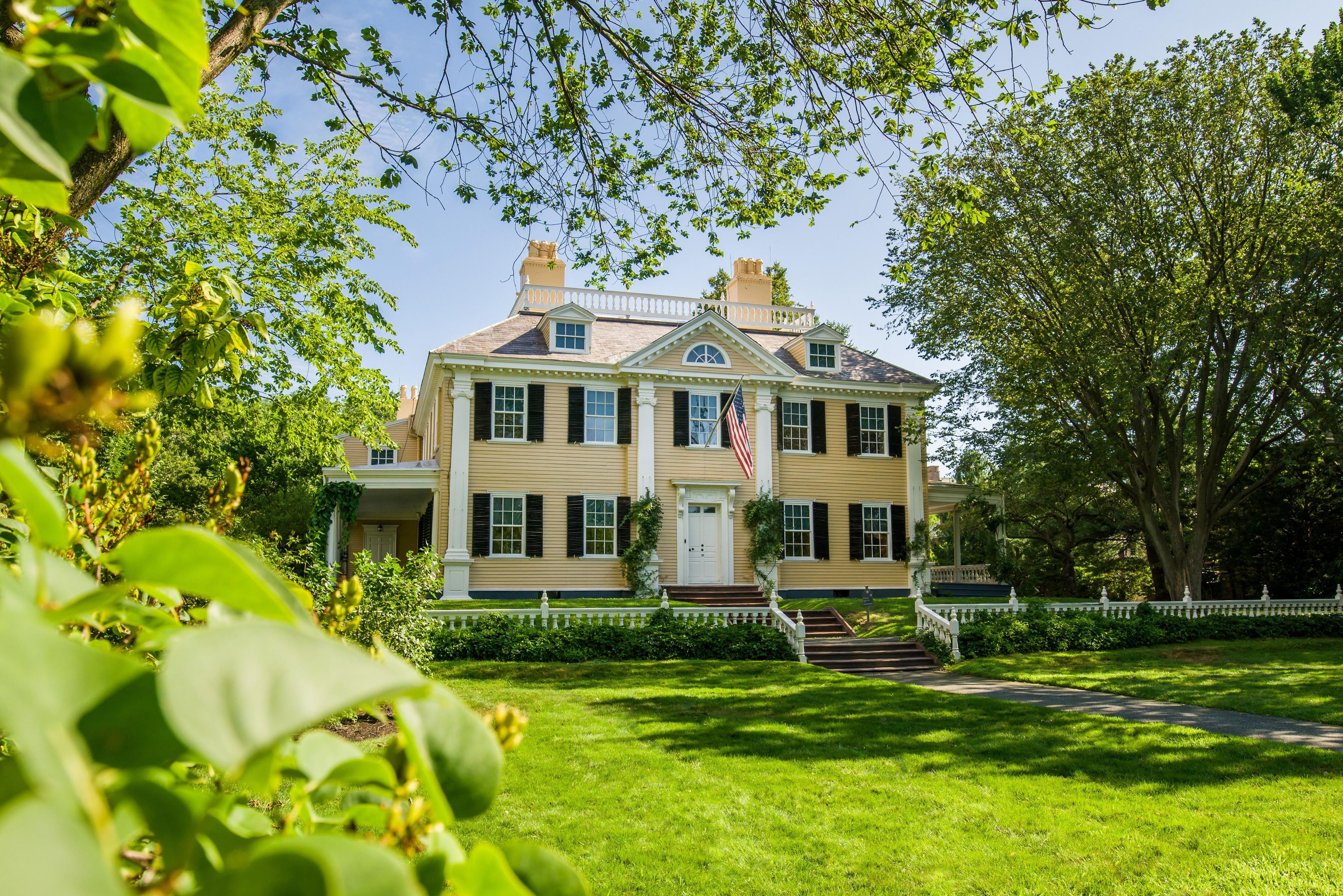 Elm trees frame the front facade of the Vassall-Craigie-Longfellow House.