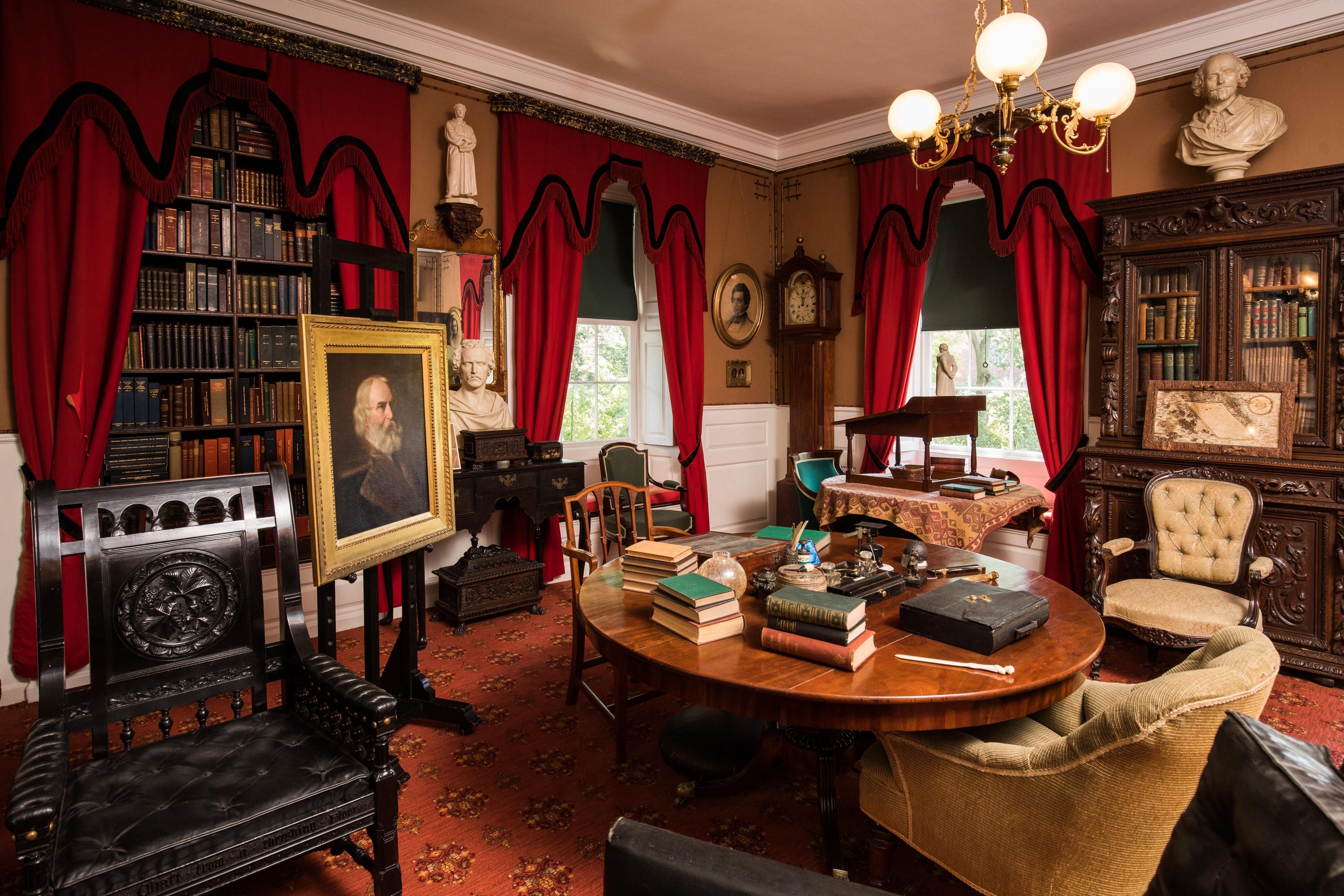 The Longfellow study table is cluttered with books and writing implements. The black "Chestnut Tree Chair" was a gift to Henry Longfellow in honor of his poem, "The Village Blacksmith."