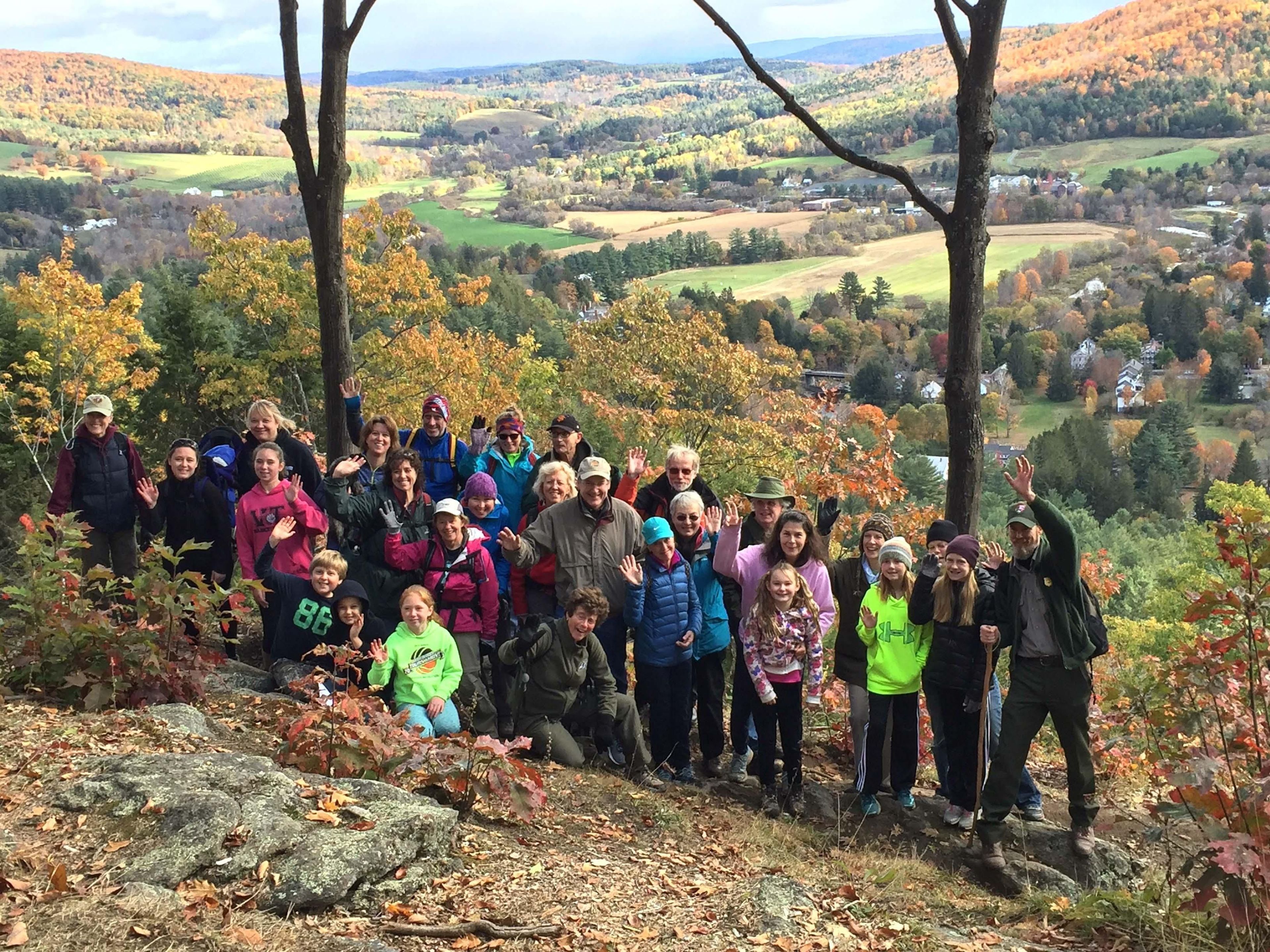 Hikers pose with ranger on Mount Tom during fall foliage on a park event