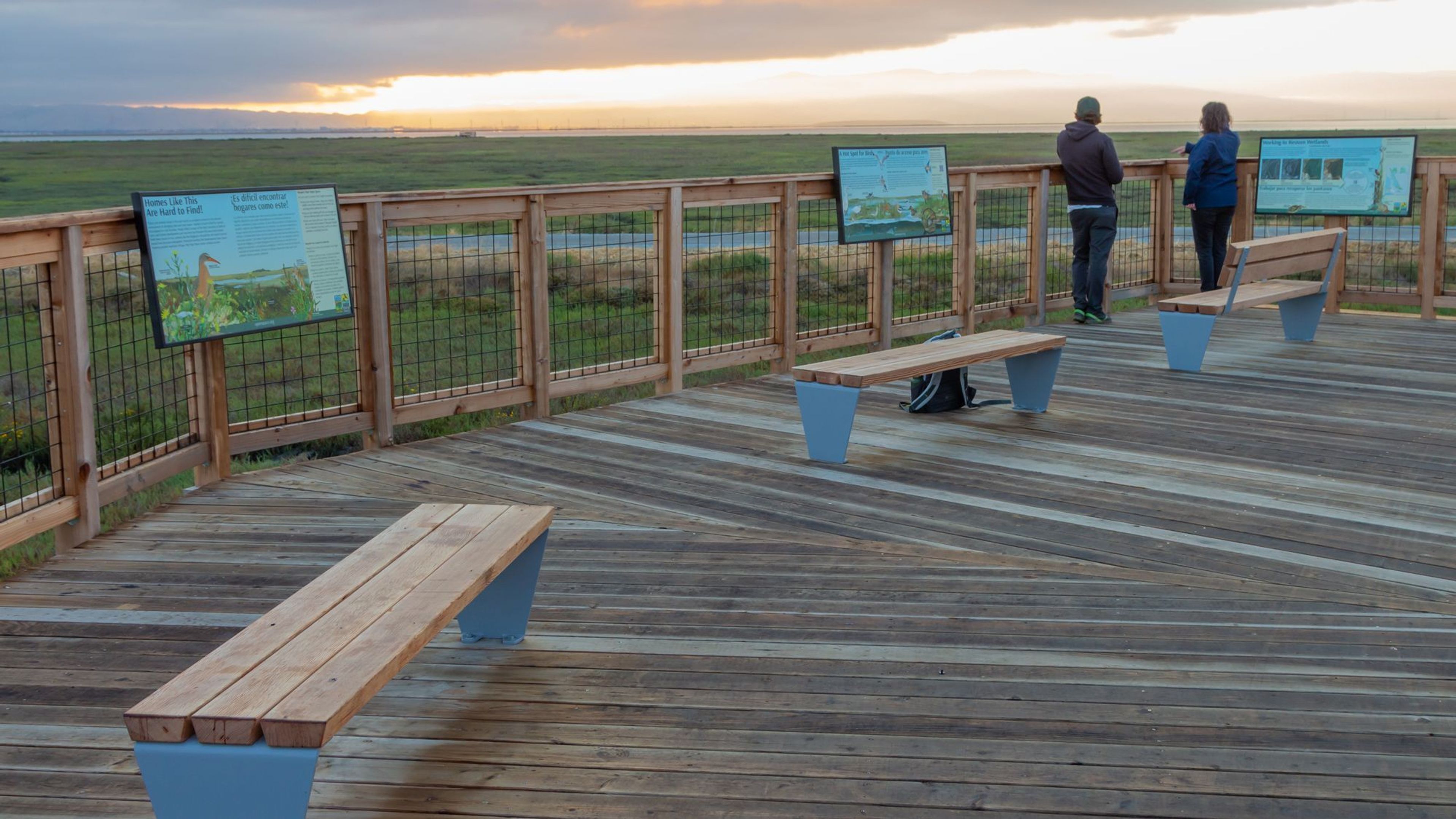 two people standing on a deck overlooking the marsh