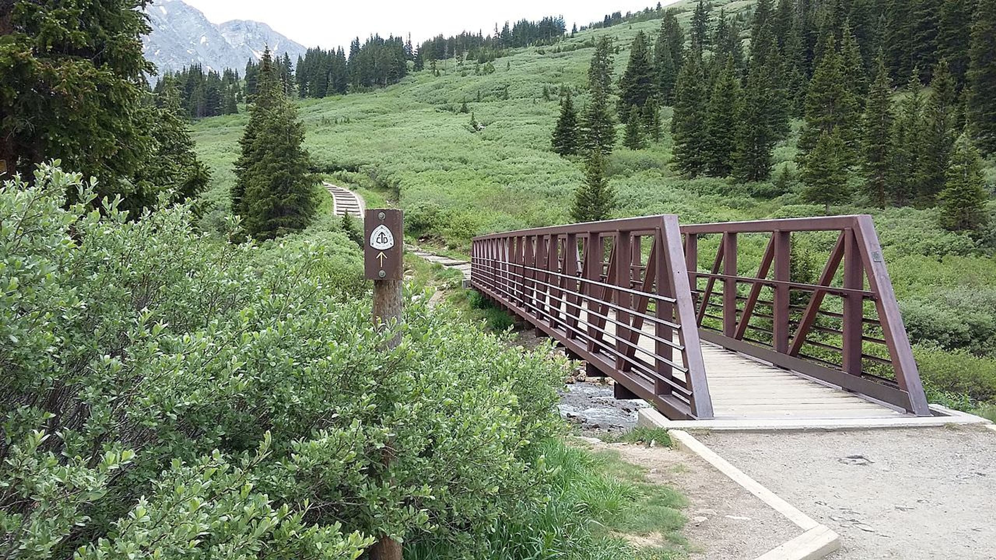 Continental Divide Trail access sign and footbridge at Grays Peak Trailhead. Photo by Xnatedawgx, wiki commons.