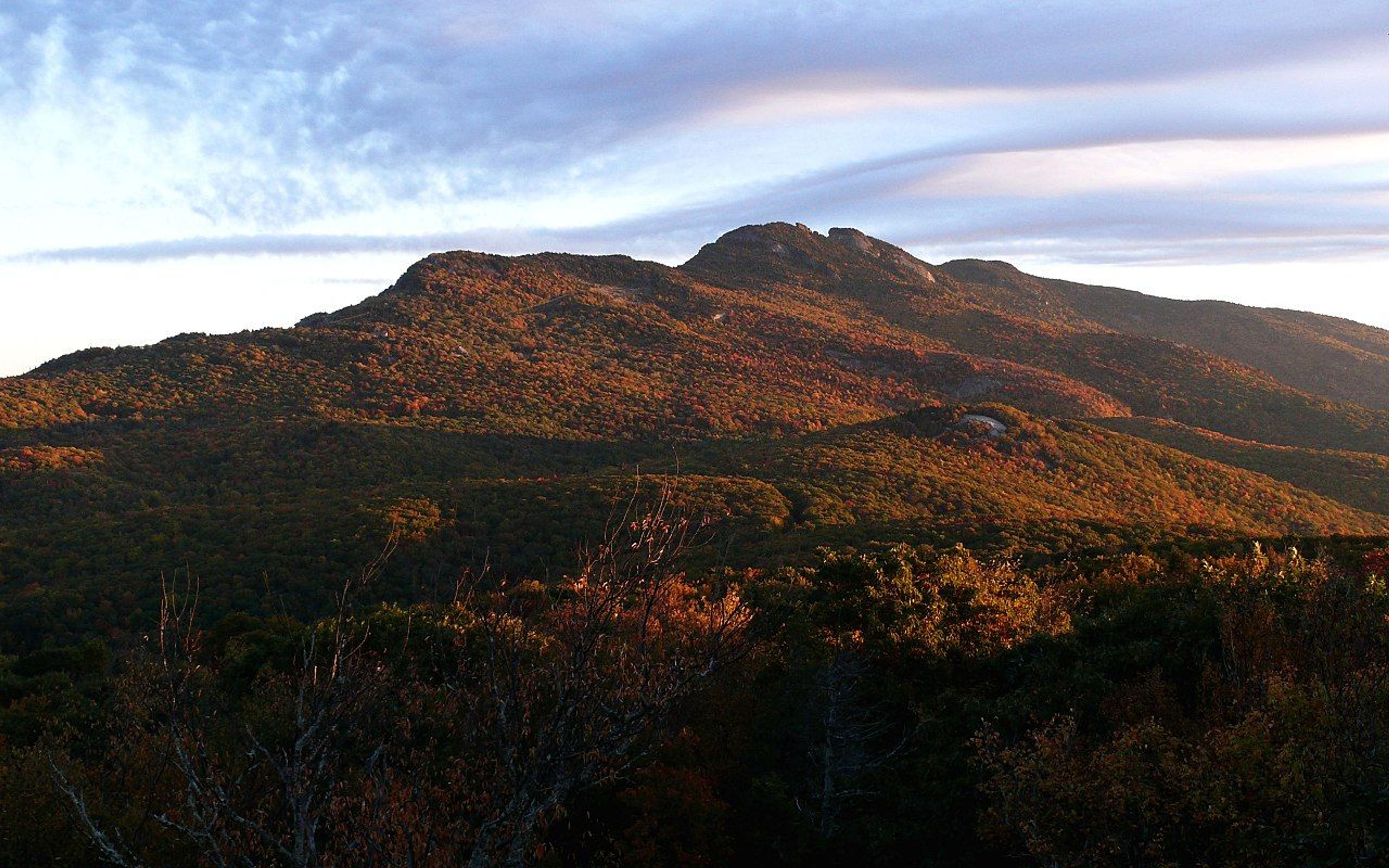 Raven Rocks and Calloway Peak, as the rising sun illuminates the brilliant fall foliage on the southeastern face of Grandfather. Photo by Ken Thomas.