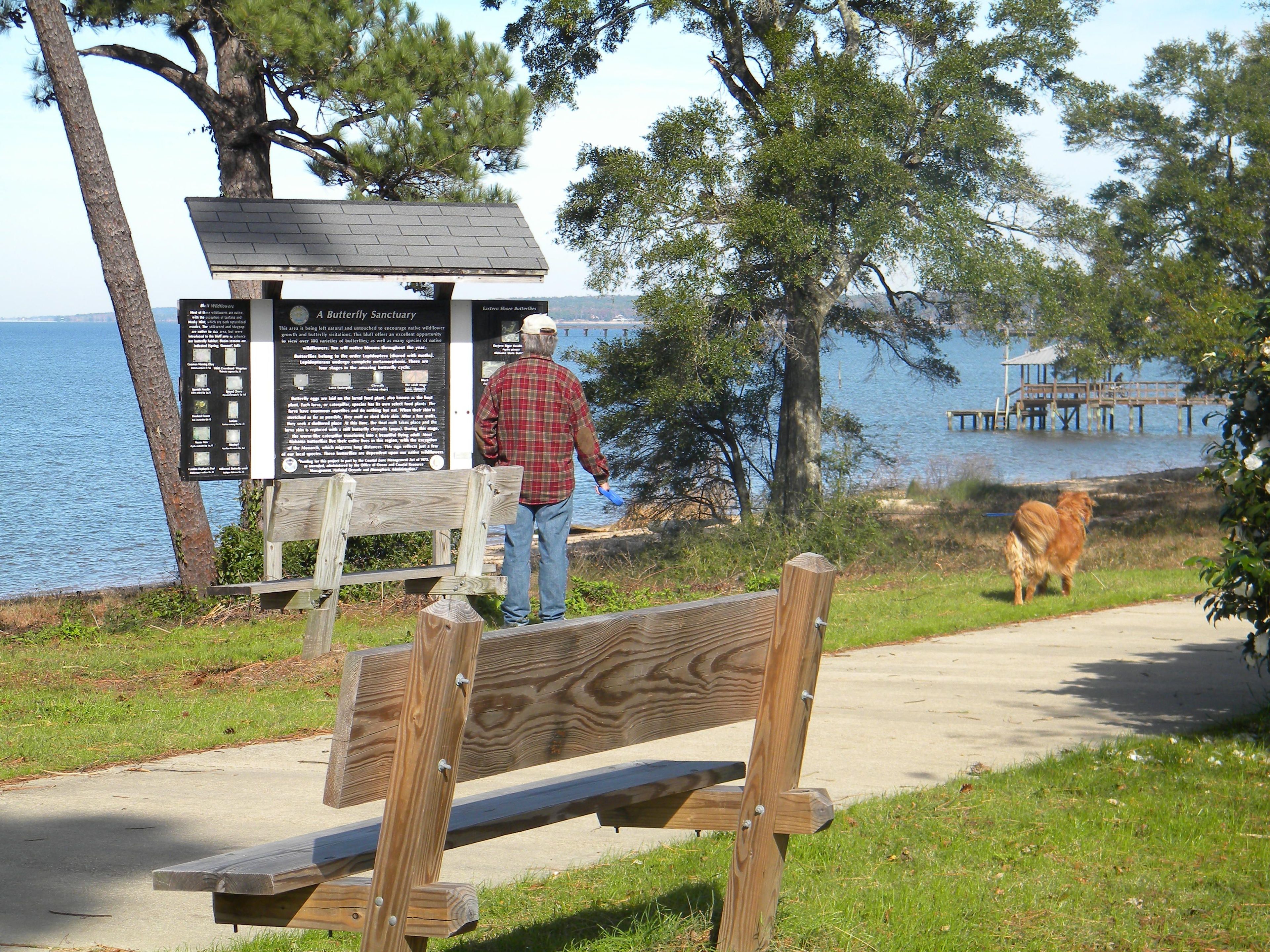 Trail walker and dog stopped at interpretive sign. Photo by Sherry Sullivan.