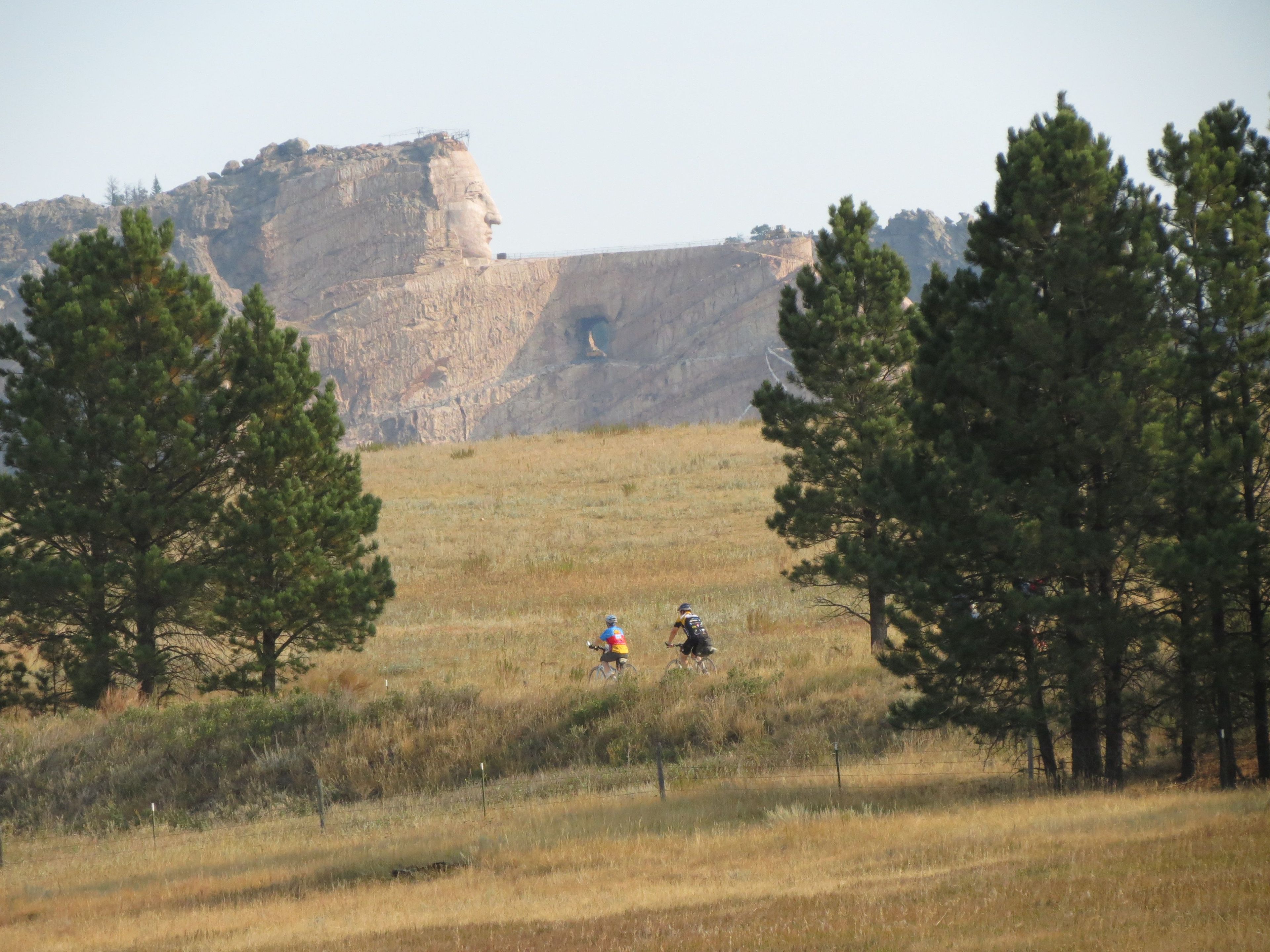 Bicyclist cruising by the Crazy Horse mountain carving. It's a work in progress that all trail users can see. Photo by Brooke Smith.