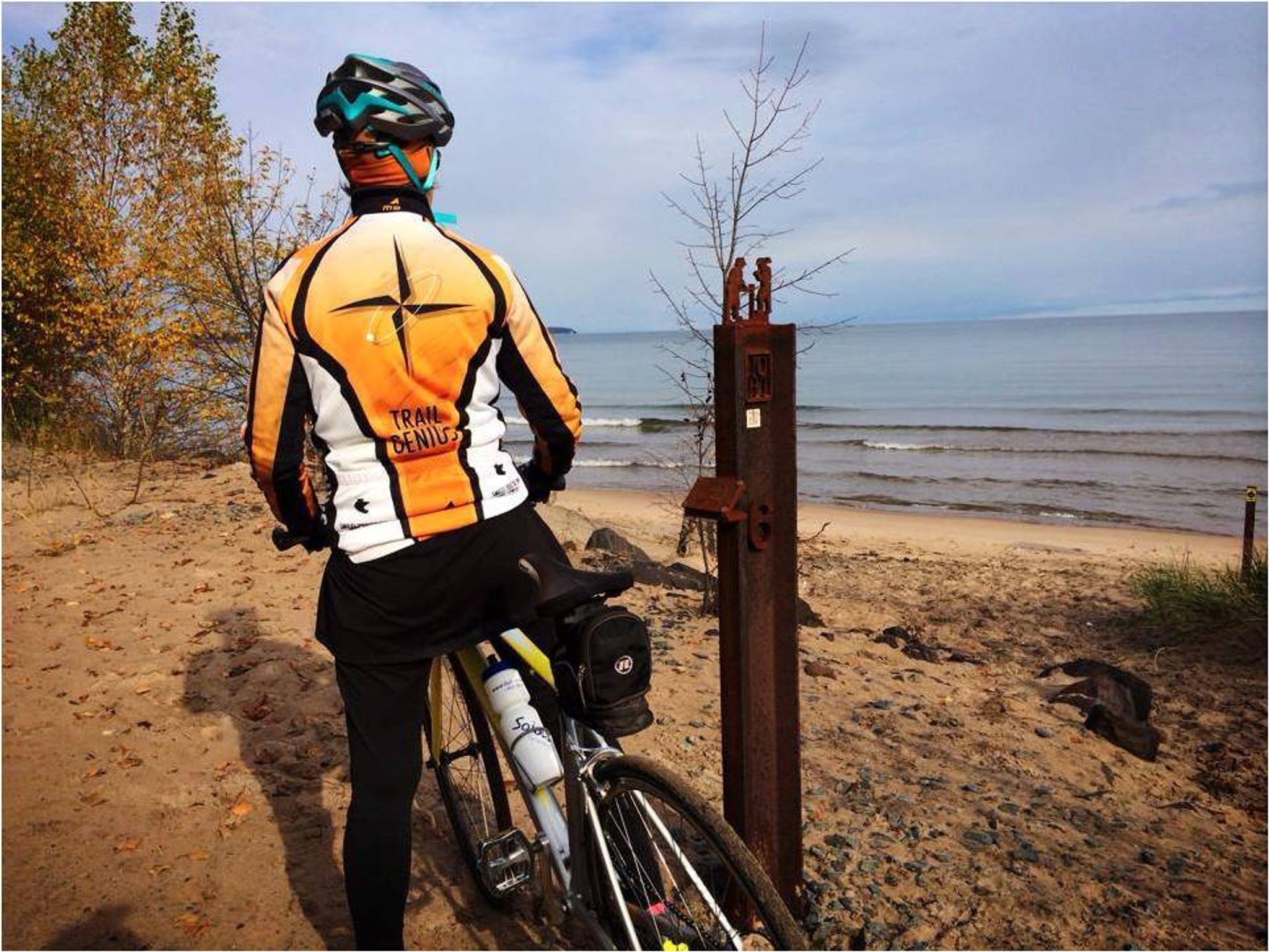 Biker at the lakeshore with one of our mile markers (made from rail used to transport ore to harbor)