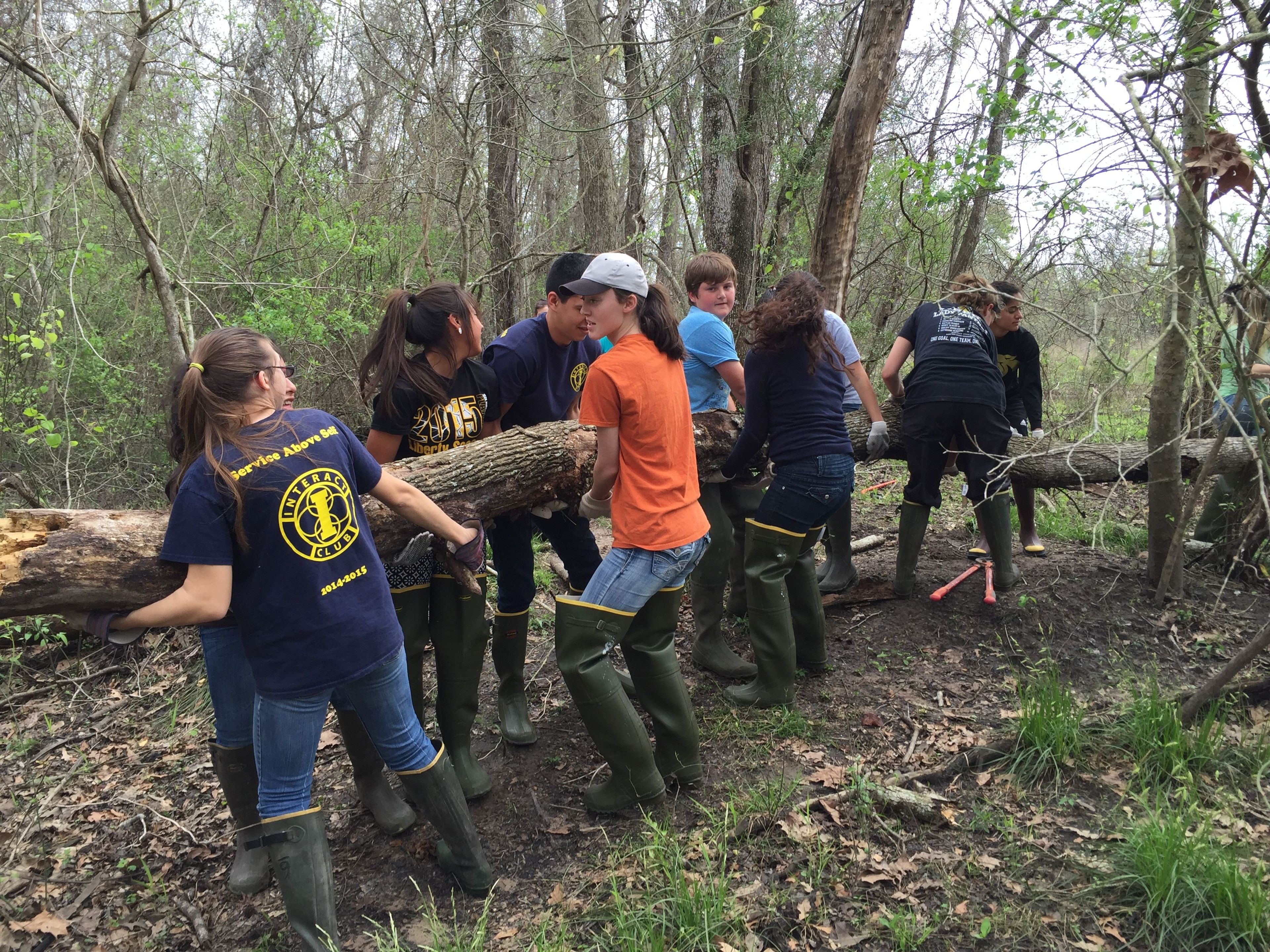 Interact Club and Leos Club Students from Liberty High School performing a group carry to move a downed log.