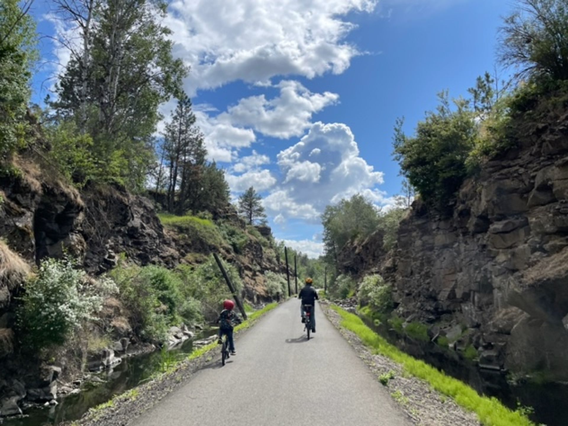 Two people biking surrounded rock walls along the Columbia Plateau State Park Trail.