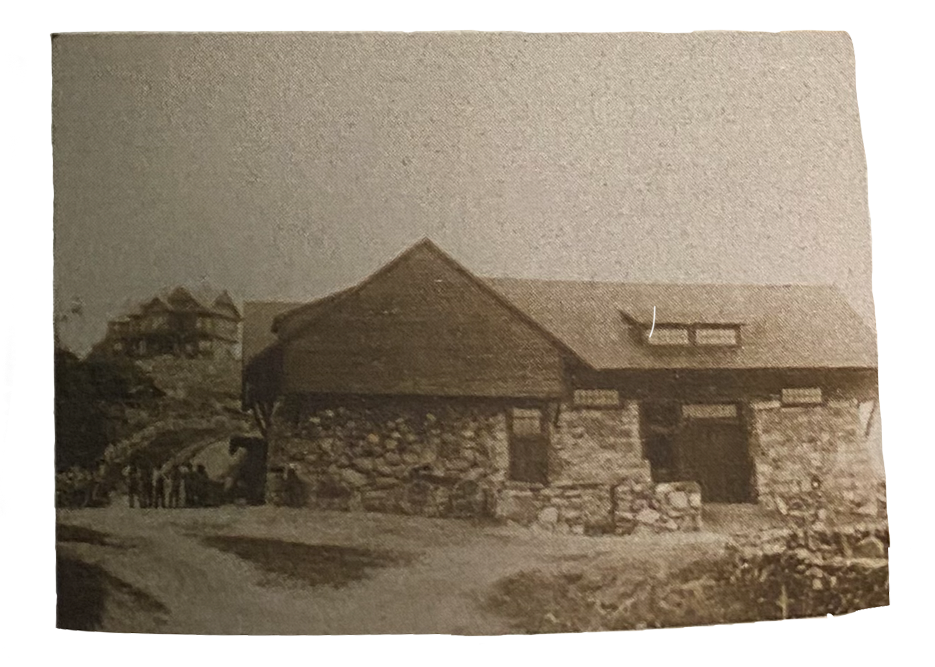 A black and white photo of the Carriage Barn with the Big House on a hill behind.