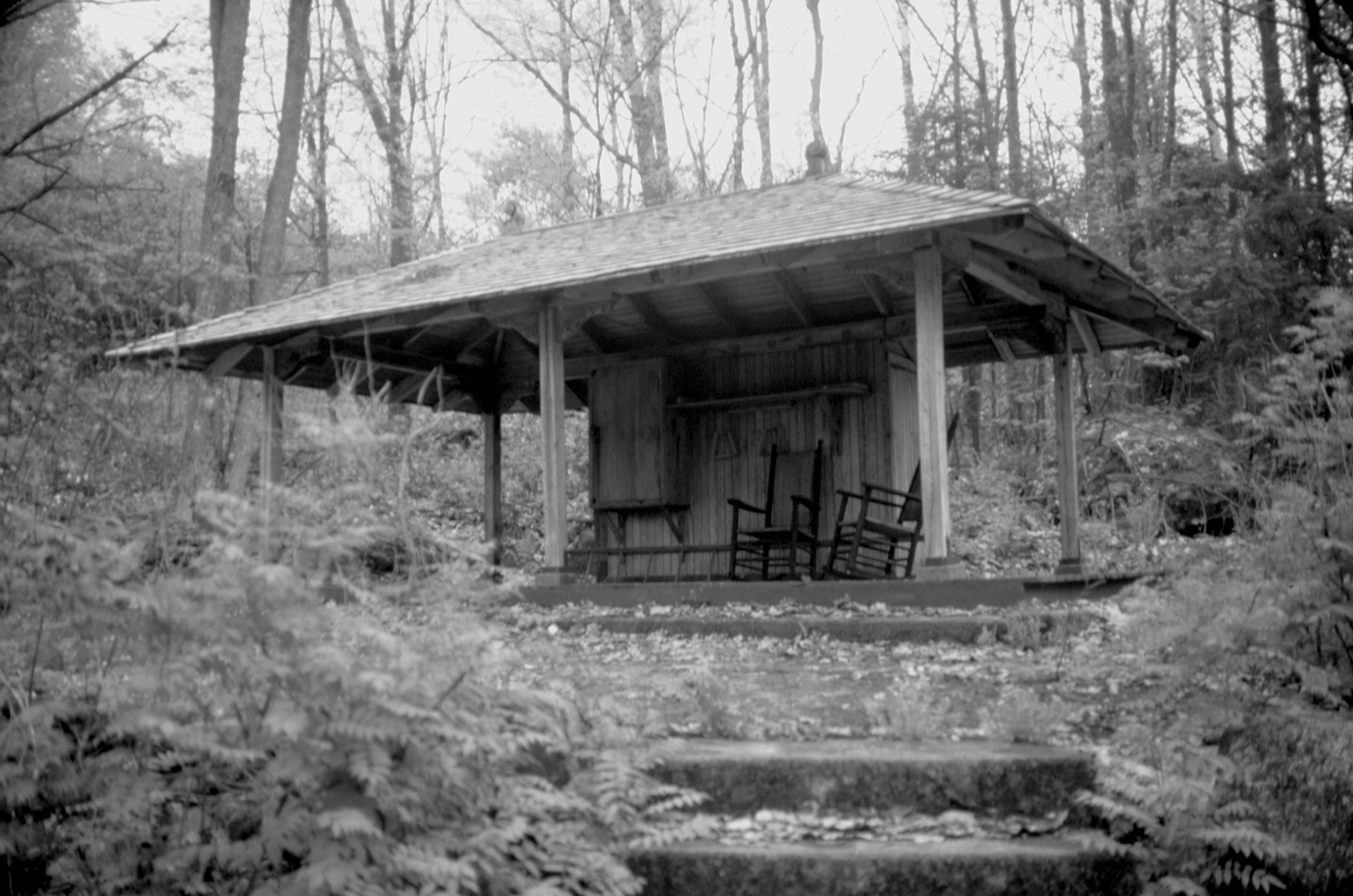 A black and white photo of the Bee House with rocking chairs out front.