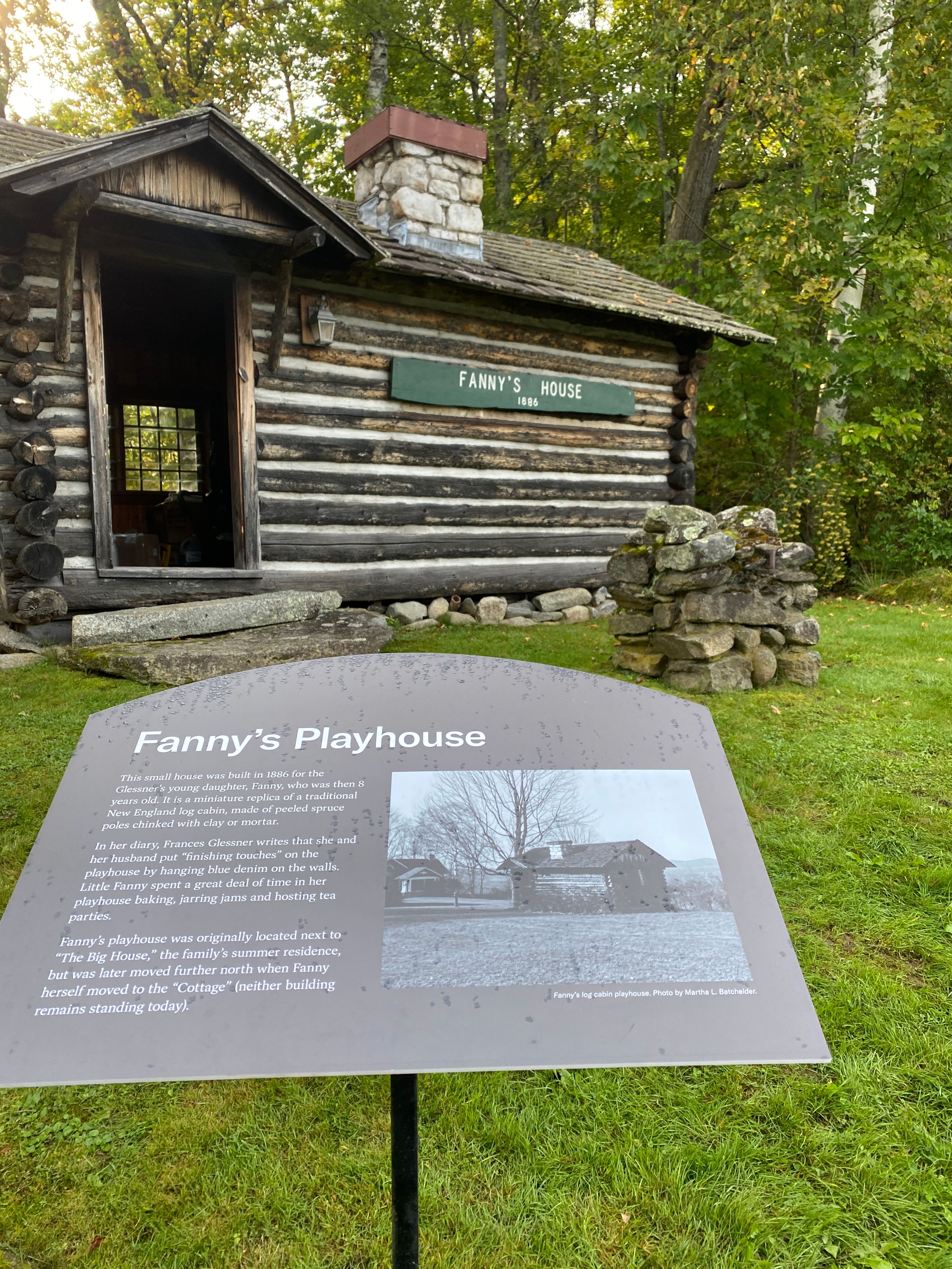 Fanny's House pictured in summer with a interpretive sign in front.