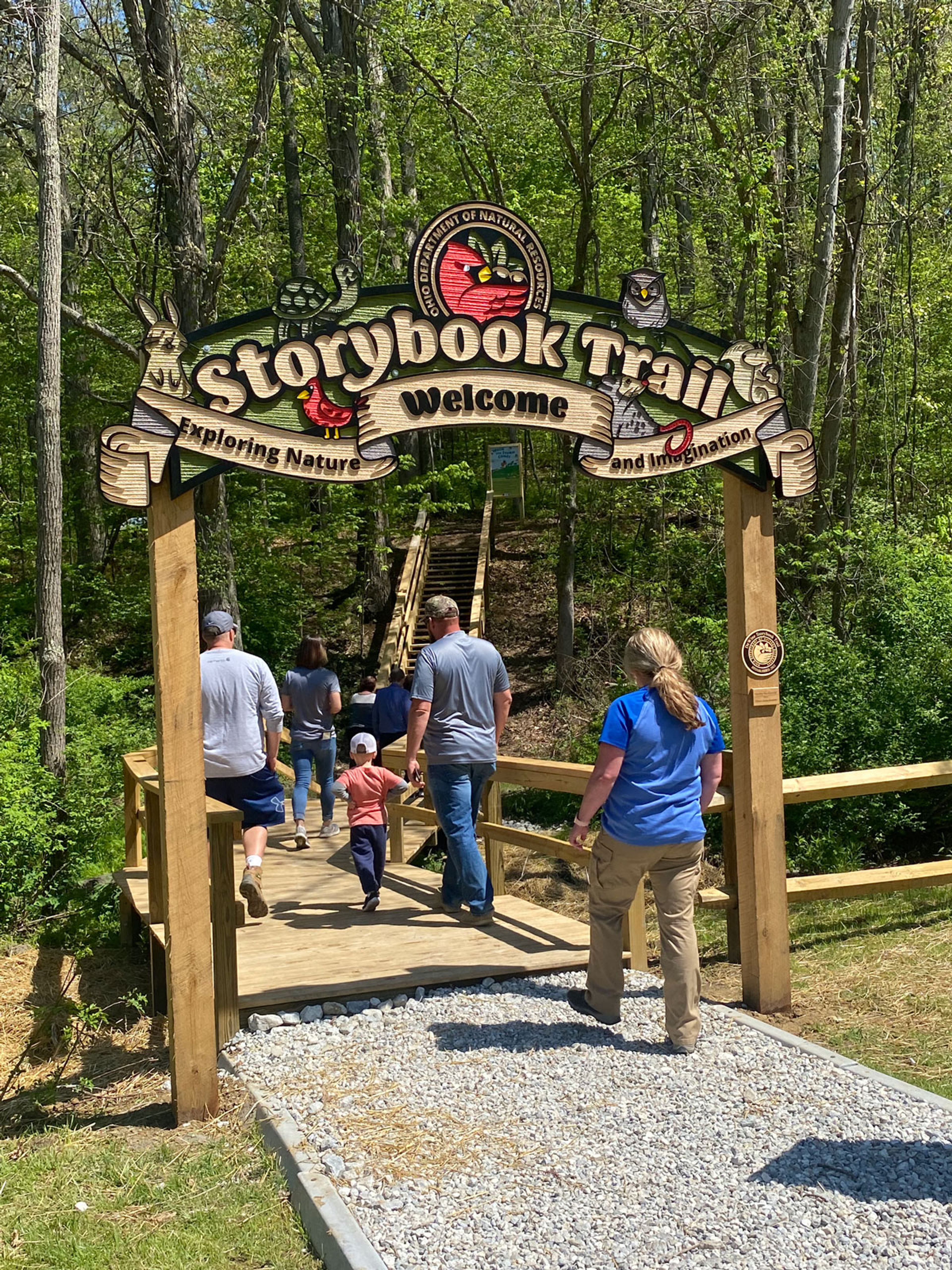 people walking on the trail at barkcamp state park at the story book trail archway signage entrance