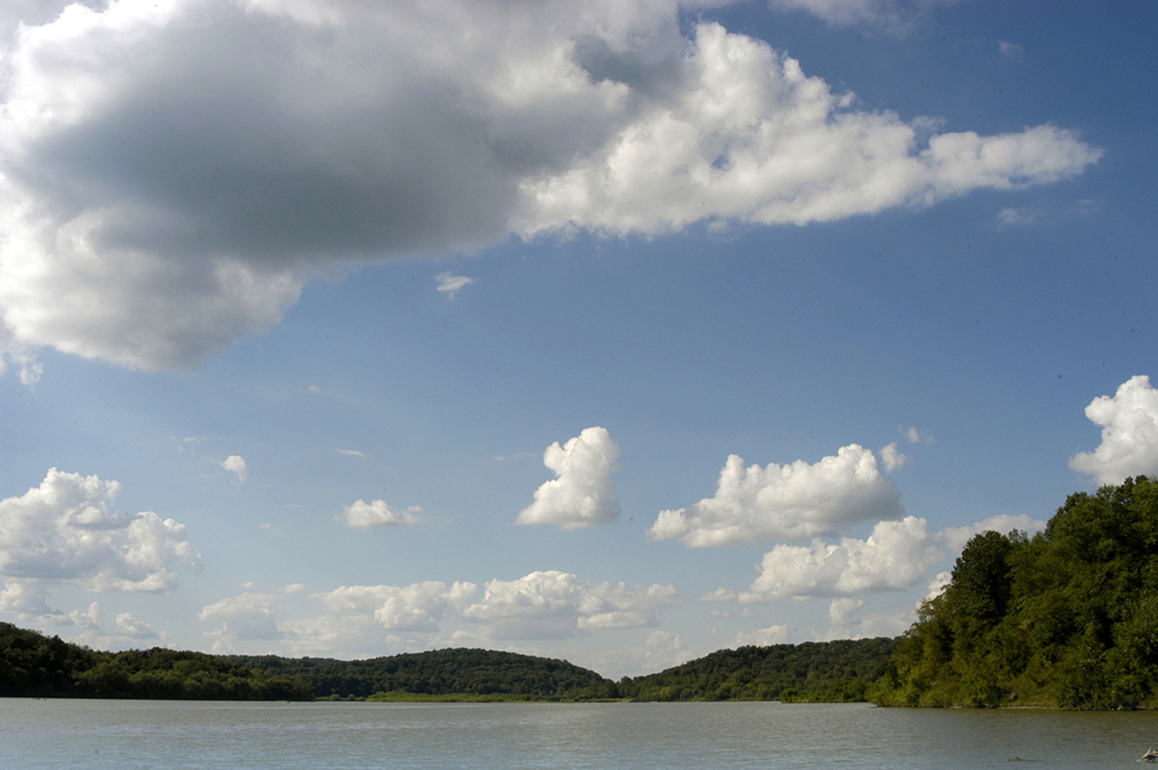 large clouds and blue skies at dillon lake with trees in the distance