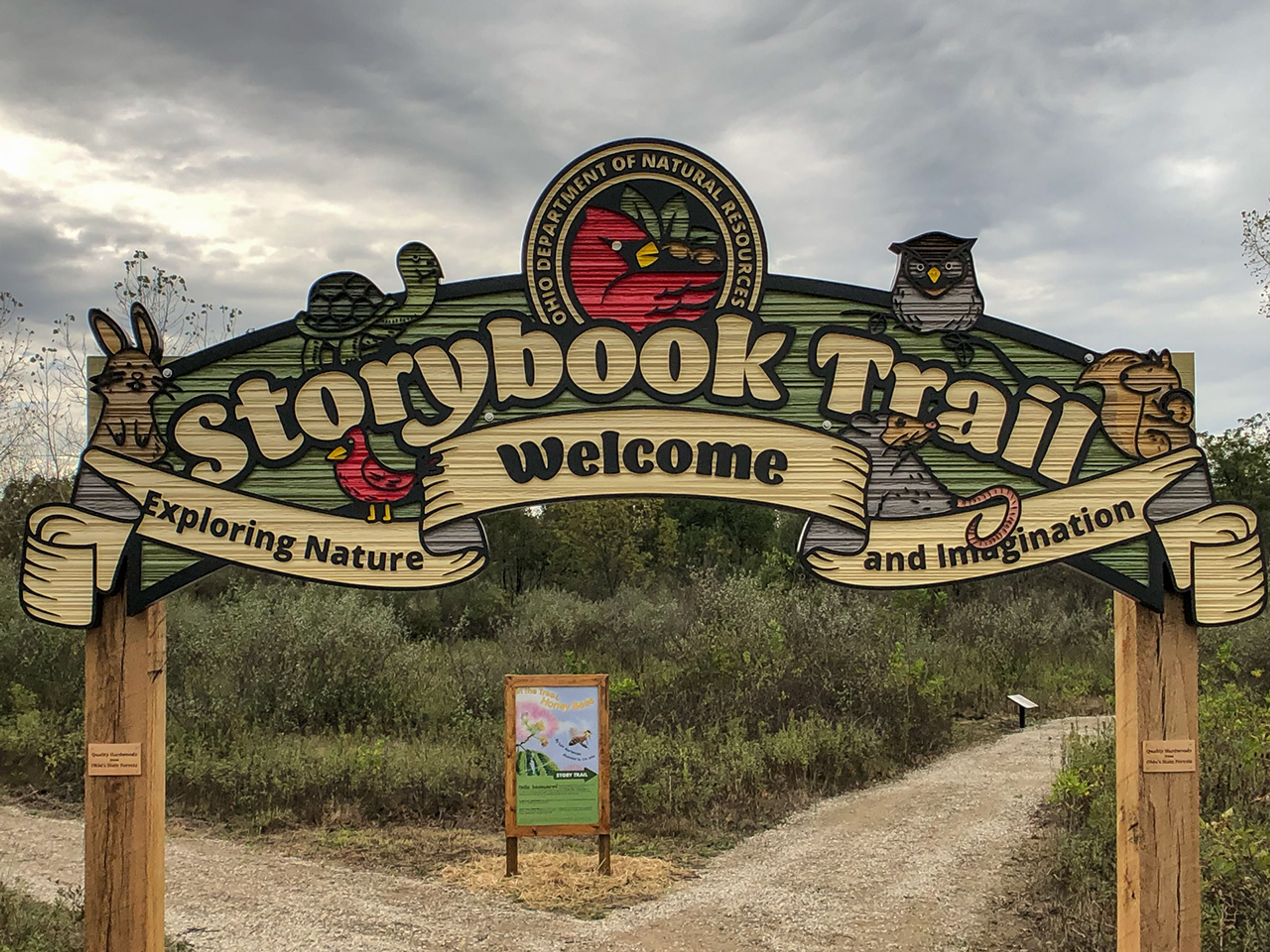 Tan and green wooden sign that says “Storybook Trail” at the start of a walking trail at Alum Creek State Park.