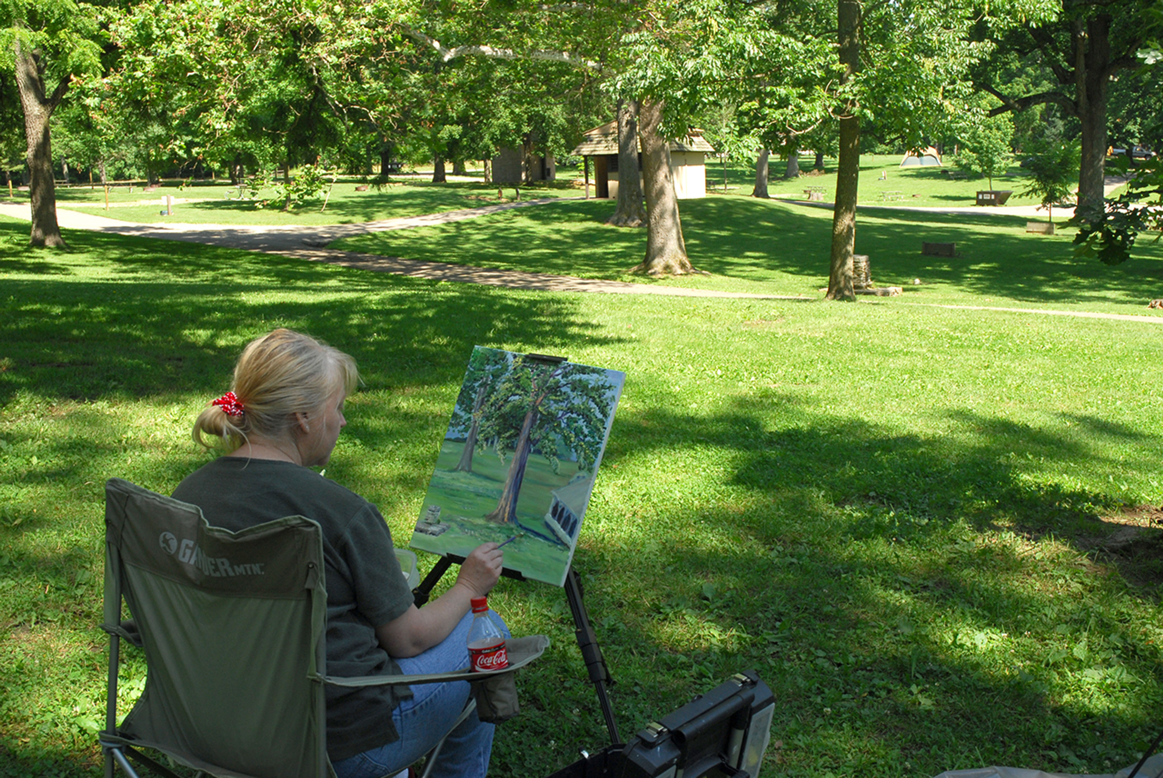 Woman outdoors painting an image of a tree at Buck Creek State Park.