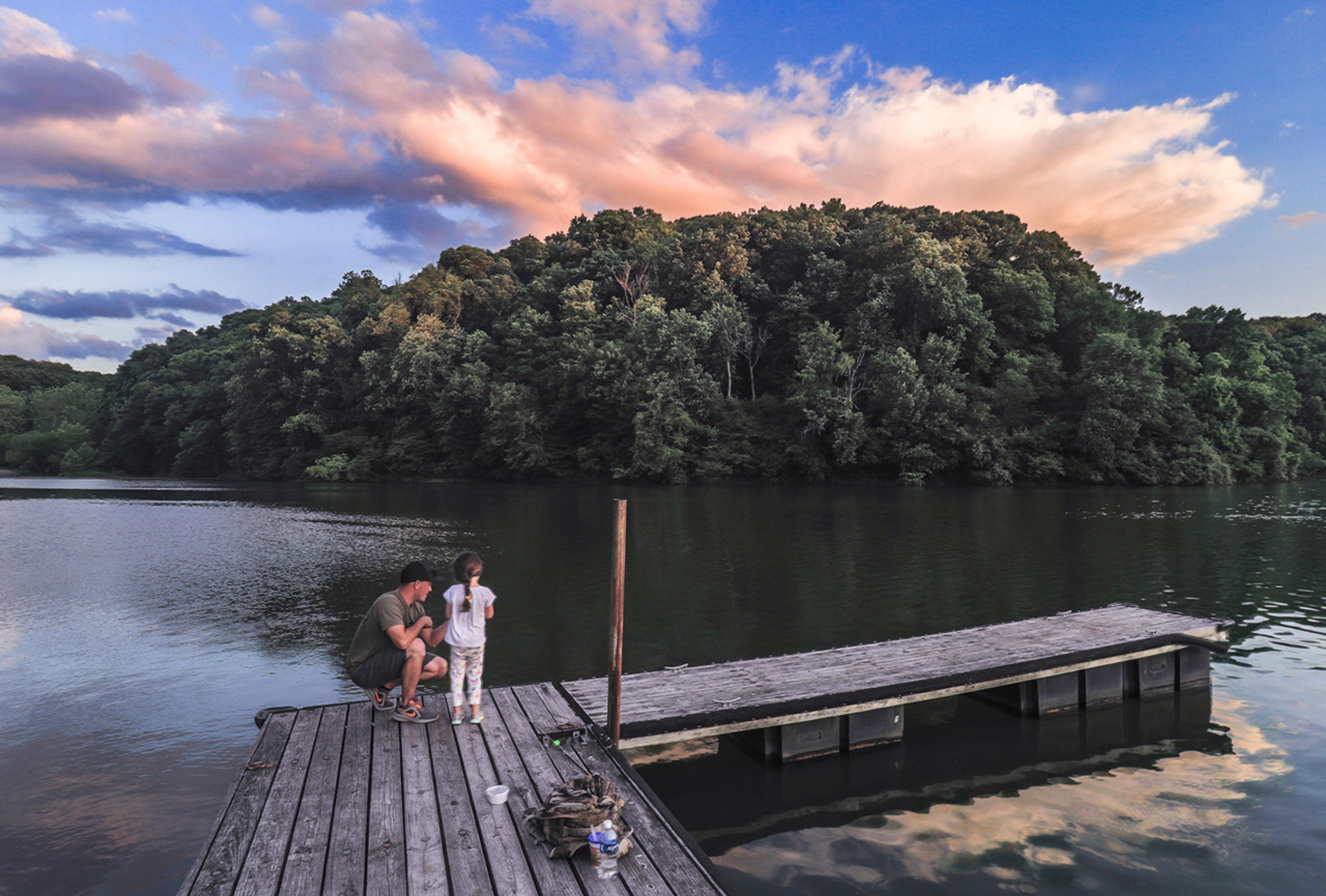 A man and child on a dock by the lake at dusk at Burr Oak State Park.