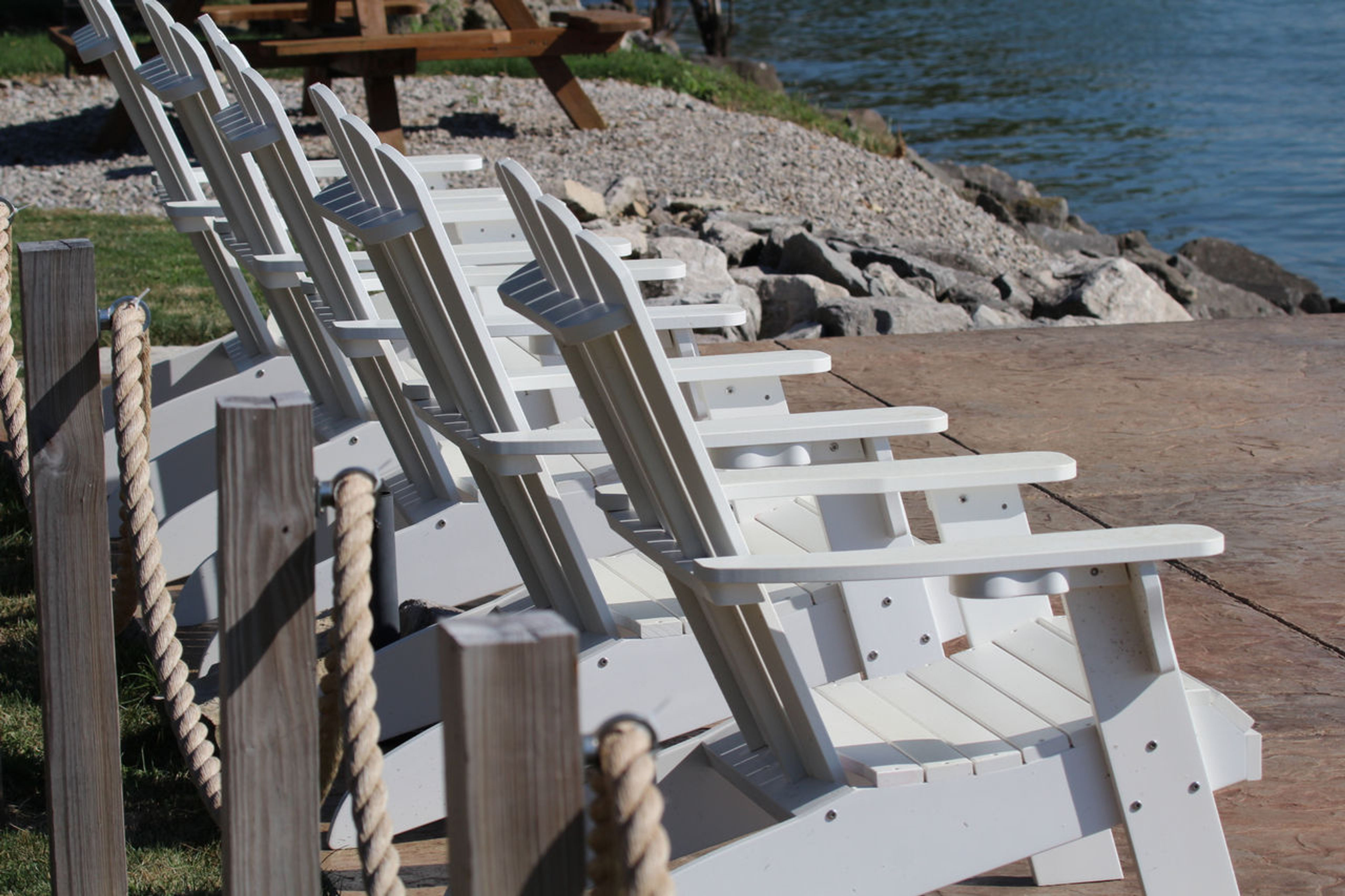 Five white chairs sitting in a row on the waterfront at Catawba Island State Park.