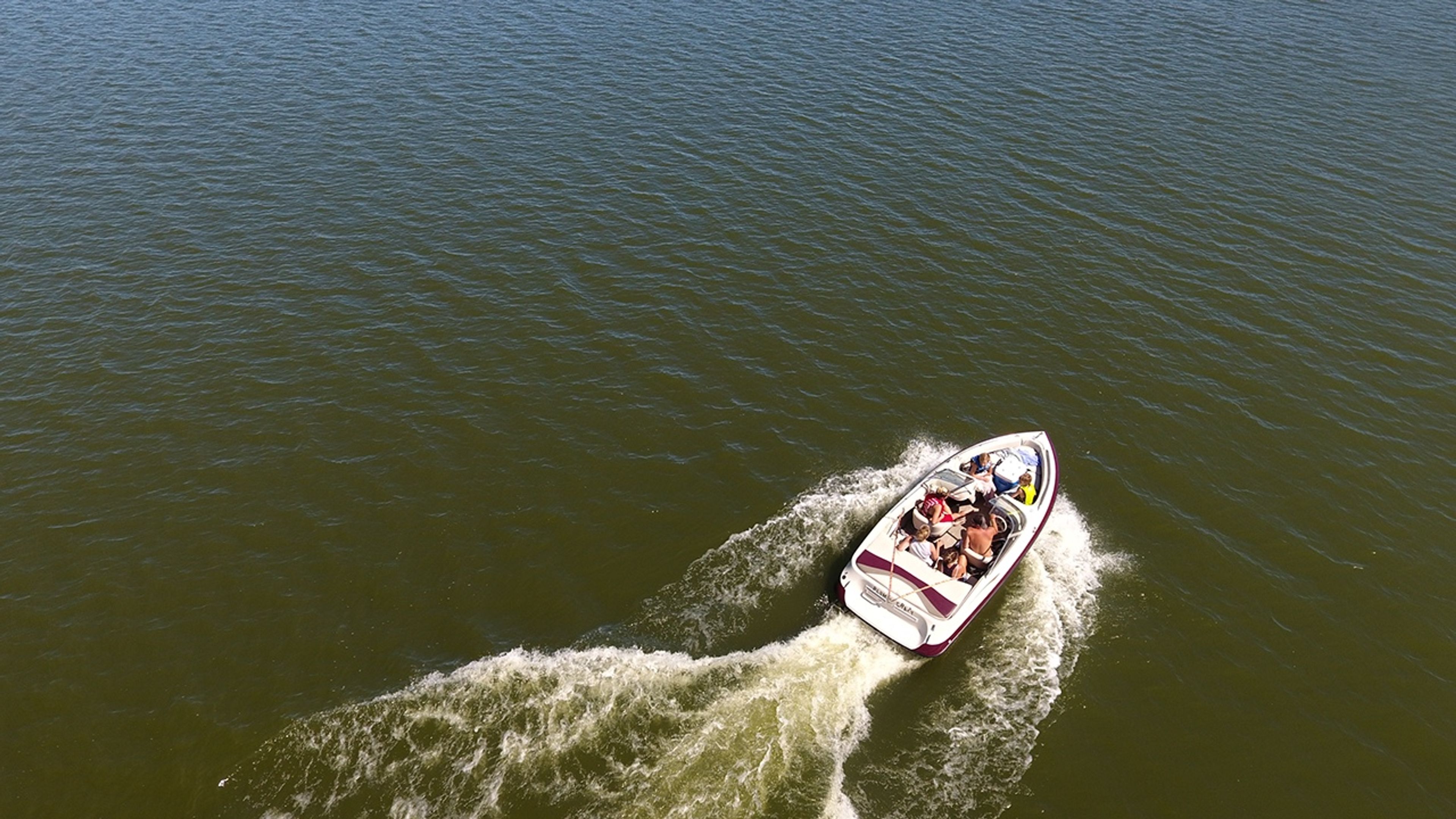 View of a group of people in a boat on the water at Deer Creek State Park.