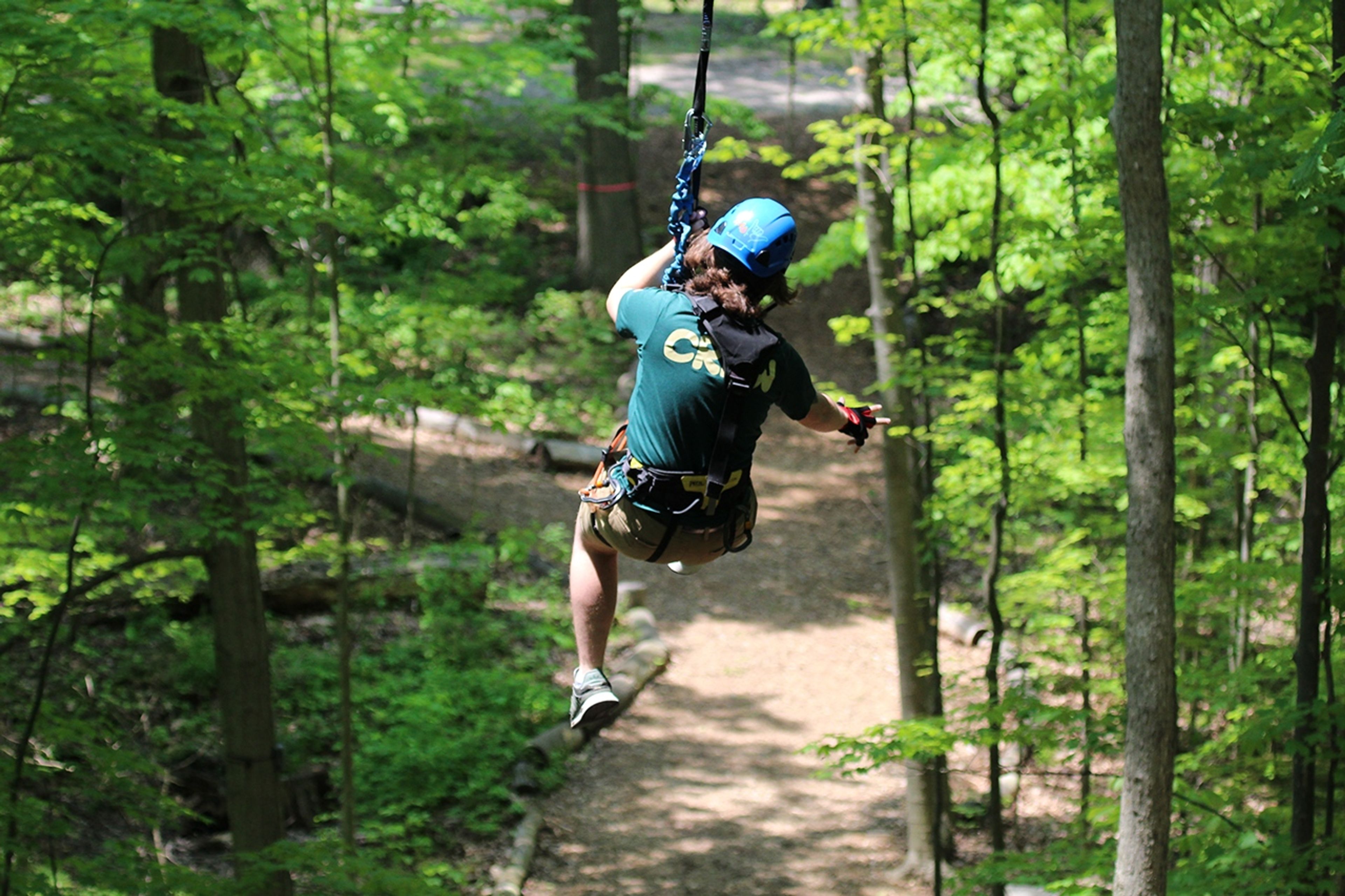 Person zip lining through a wooded area at Geneva State Park