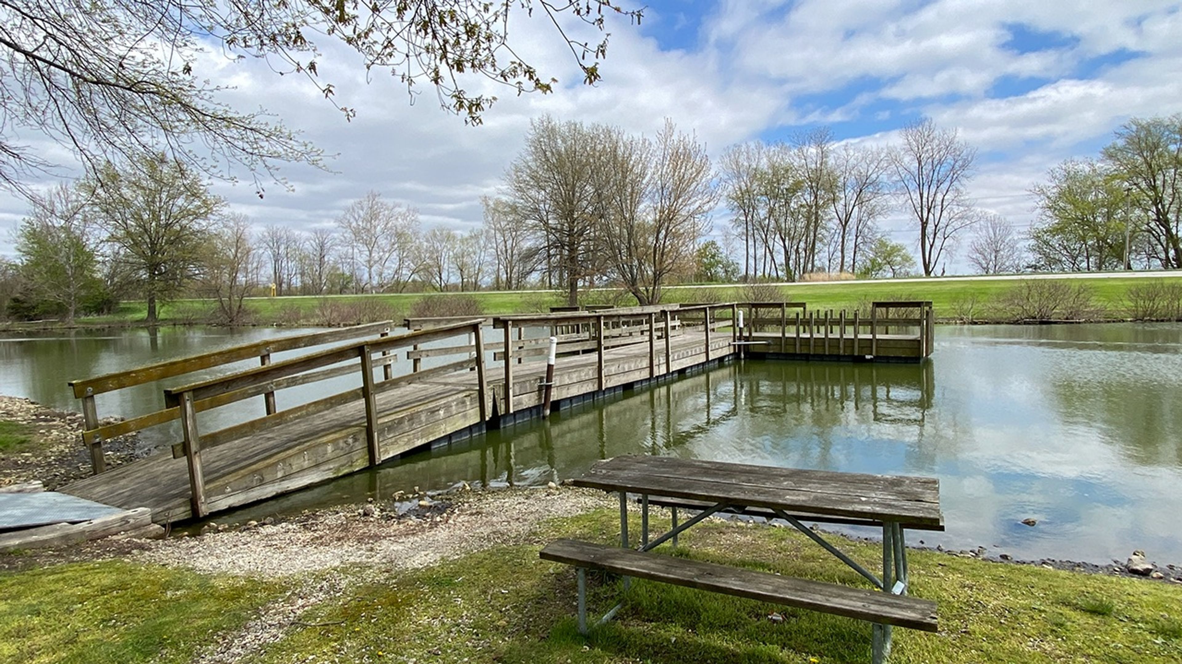 A wooden dock with benches and a lake at Grand Lake St Marys State Park