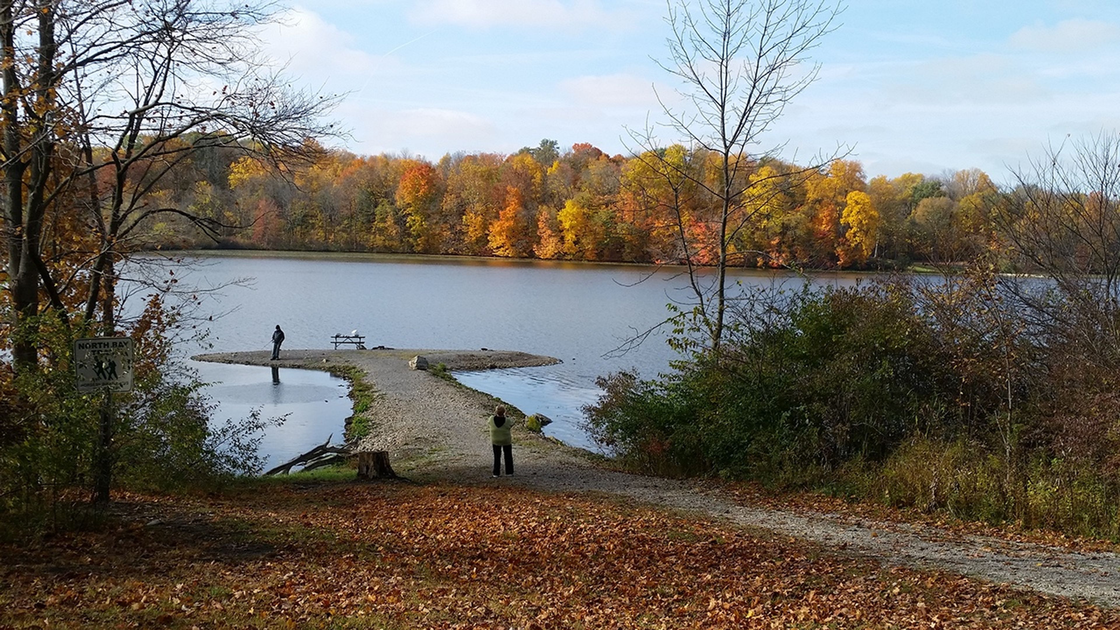 A group of people standing on a paved walkway out on a lake at Kiser Lake State Park