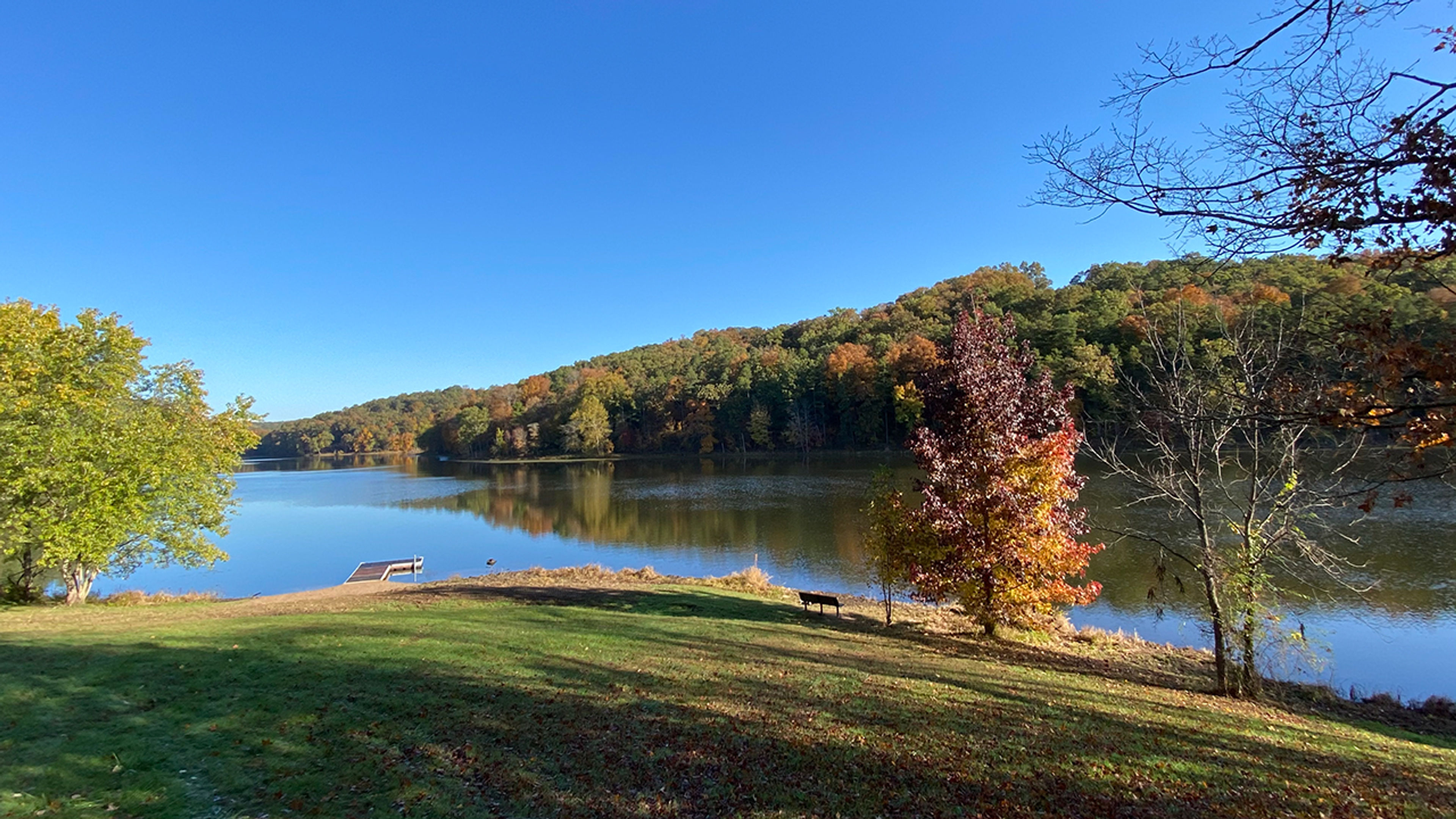 A lake with a small dock and trees in the background at Lake Hope State Park