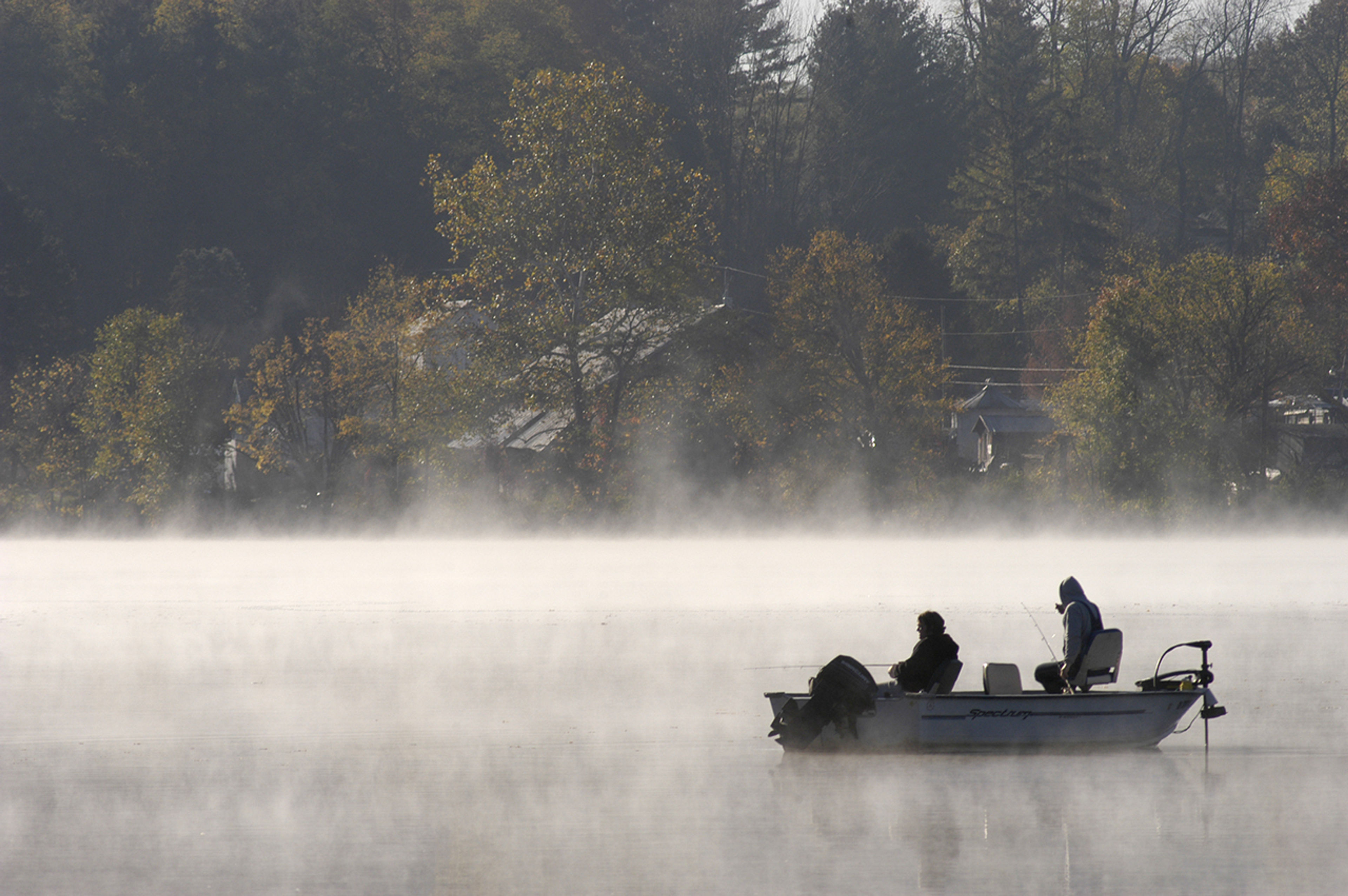 A group of people in a boat on a foggy lake at Lake Logan State Park