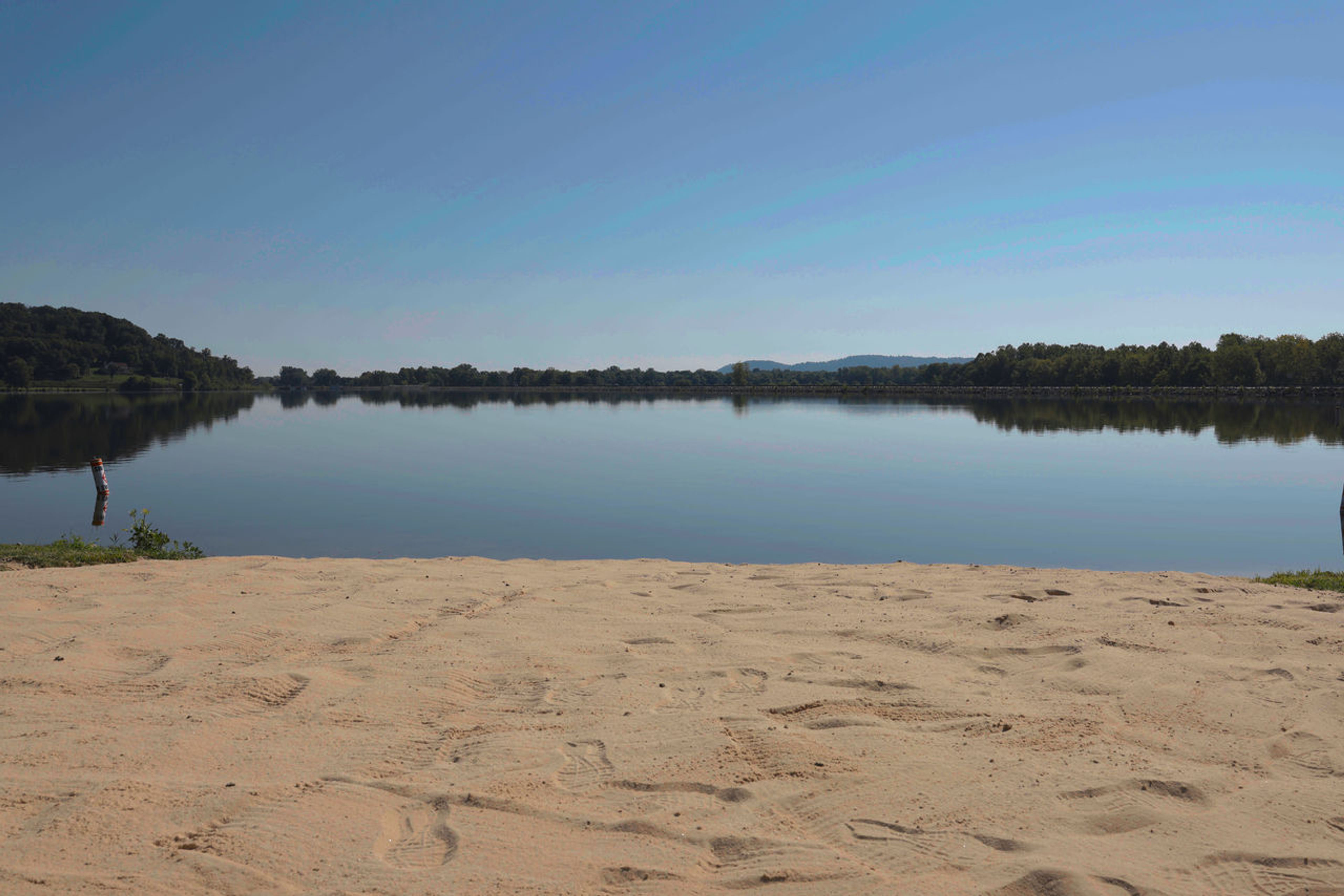 A sandy beach with trees in the background at Lake White State Park