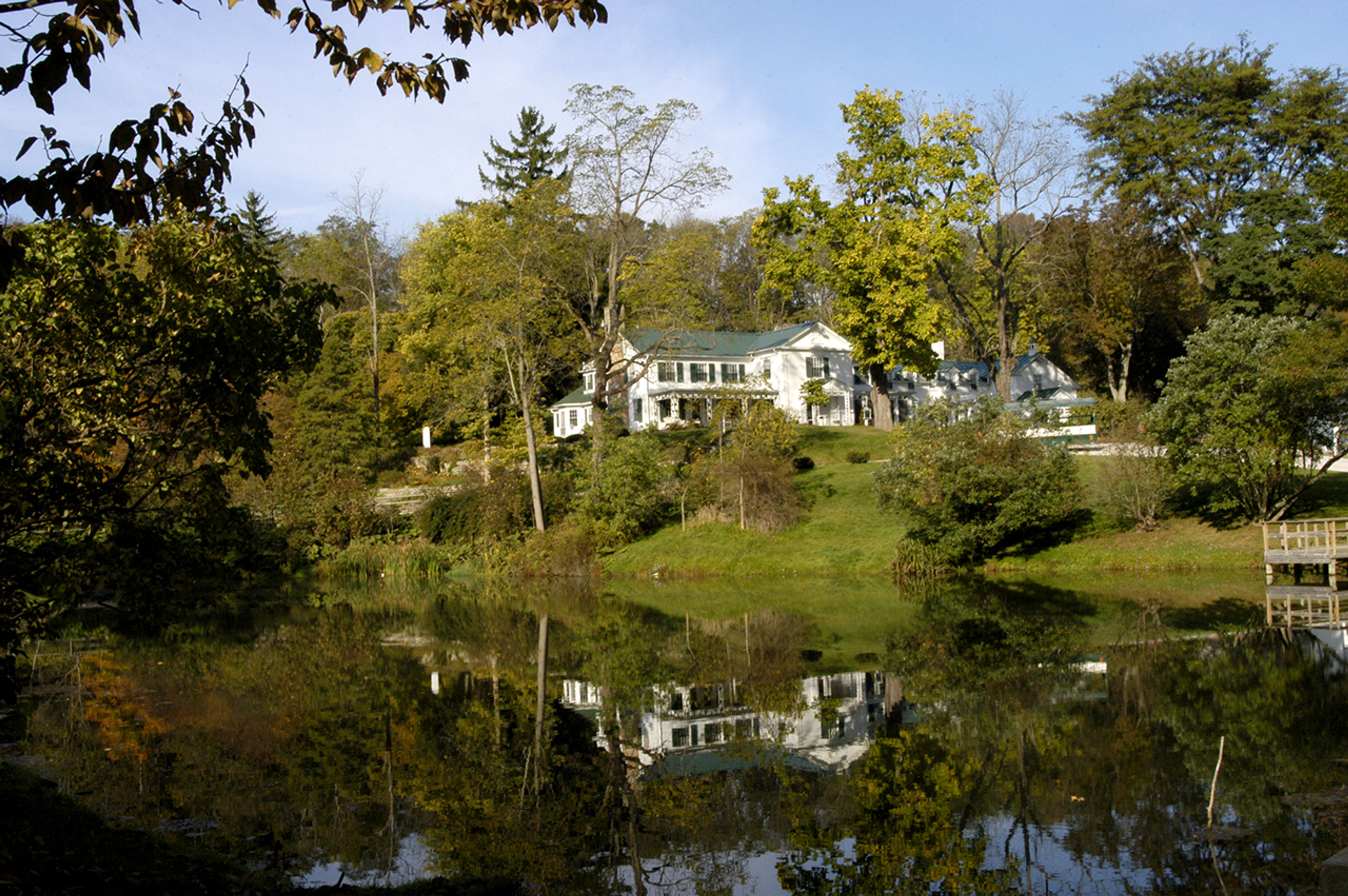 A white farm house on the hill by a body of water at Malabar Farm State Park