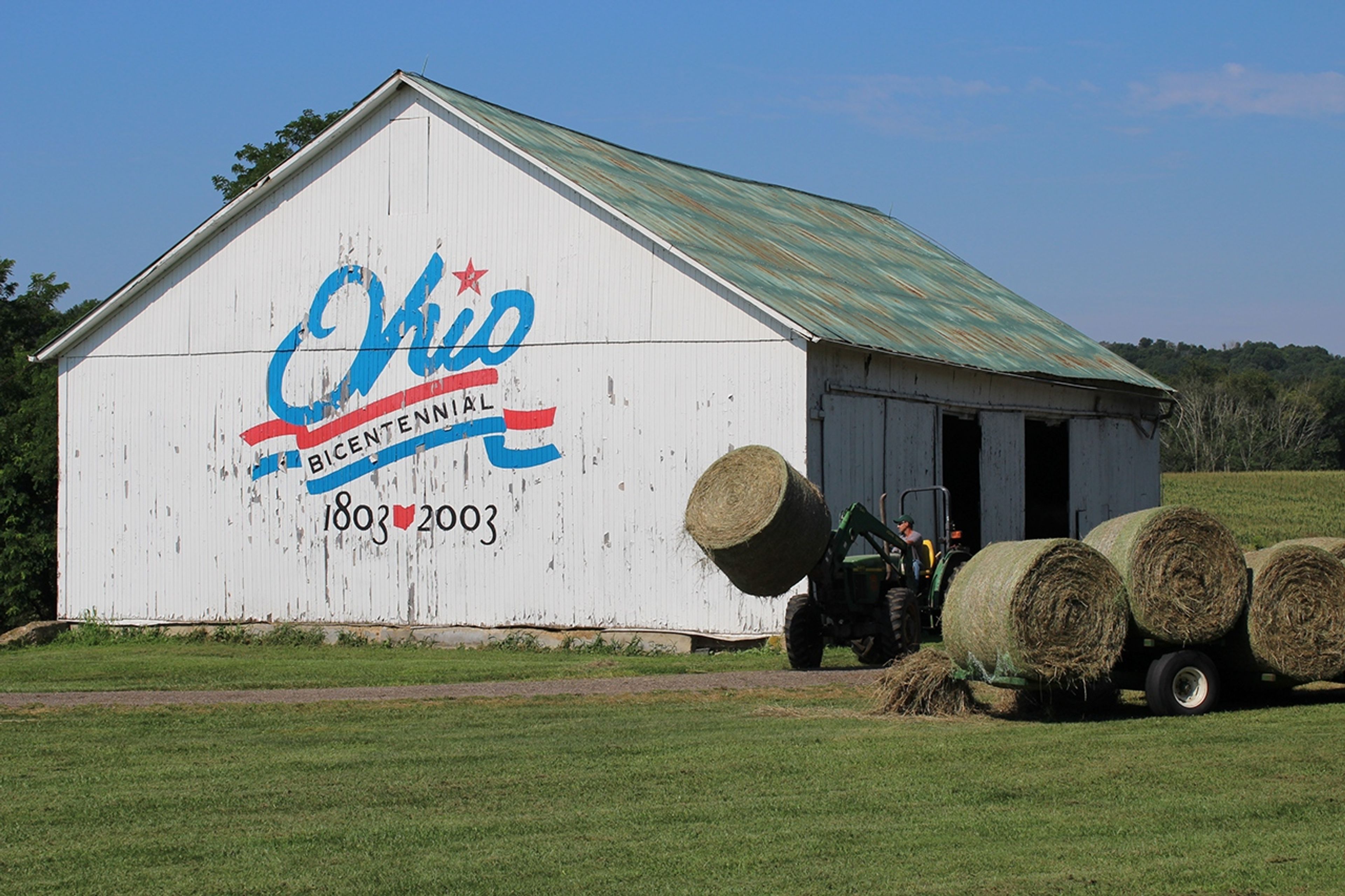 A tractor pulling hay bales out of a barn at Malabar Farm State Park