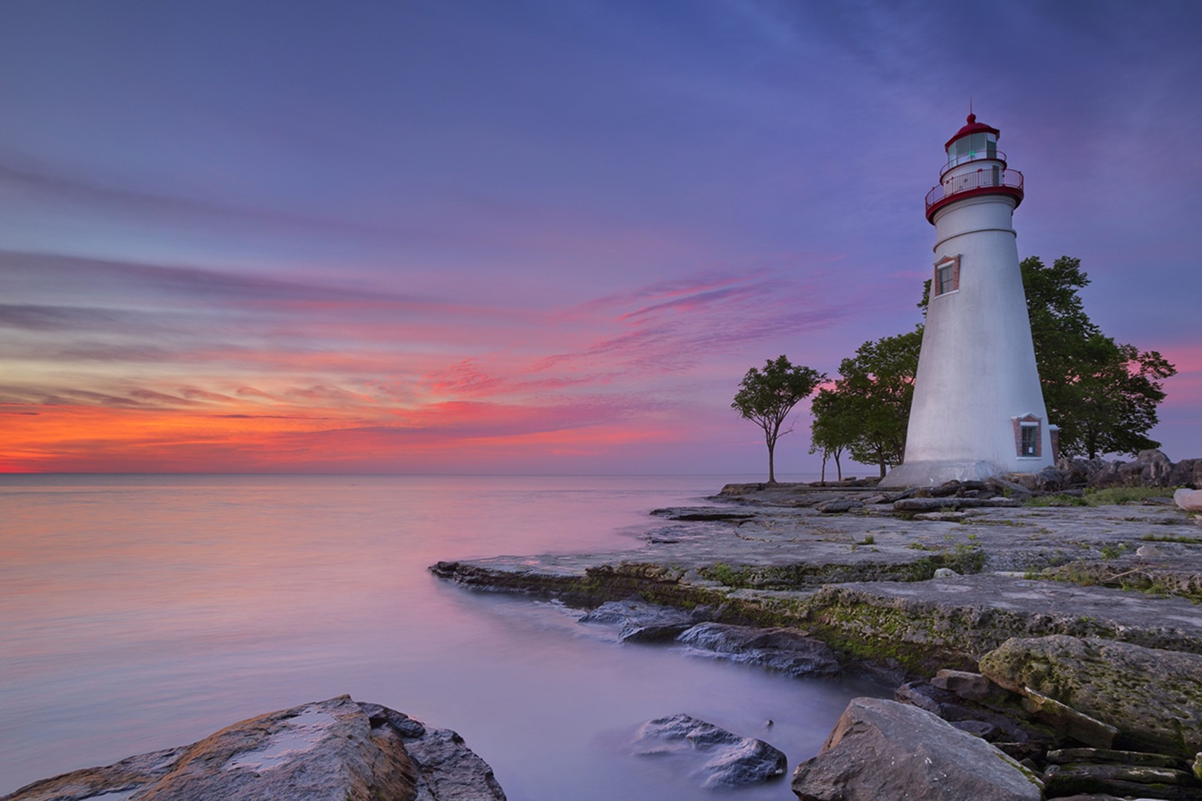 A lighthouse on a rocky shore at sunset at Marblehead Lighthouse State Park