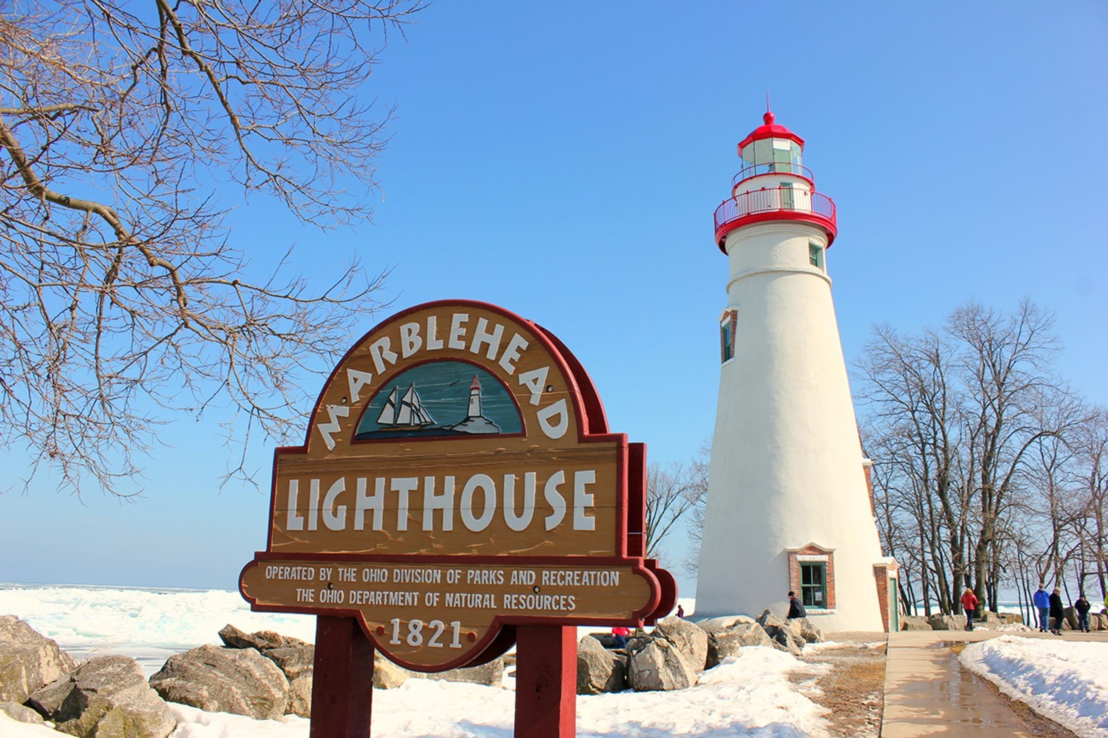 Sign that reads Marblehead Lighthouse in front of a white lighthouse at Marblehead Lighthouse State Park