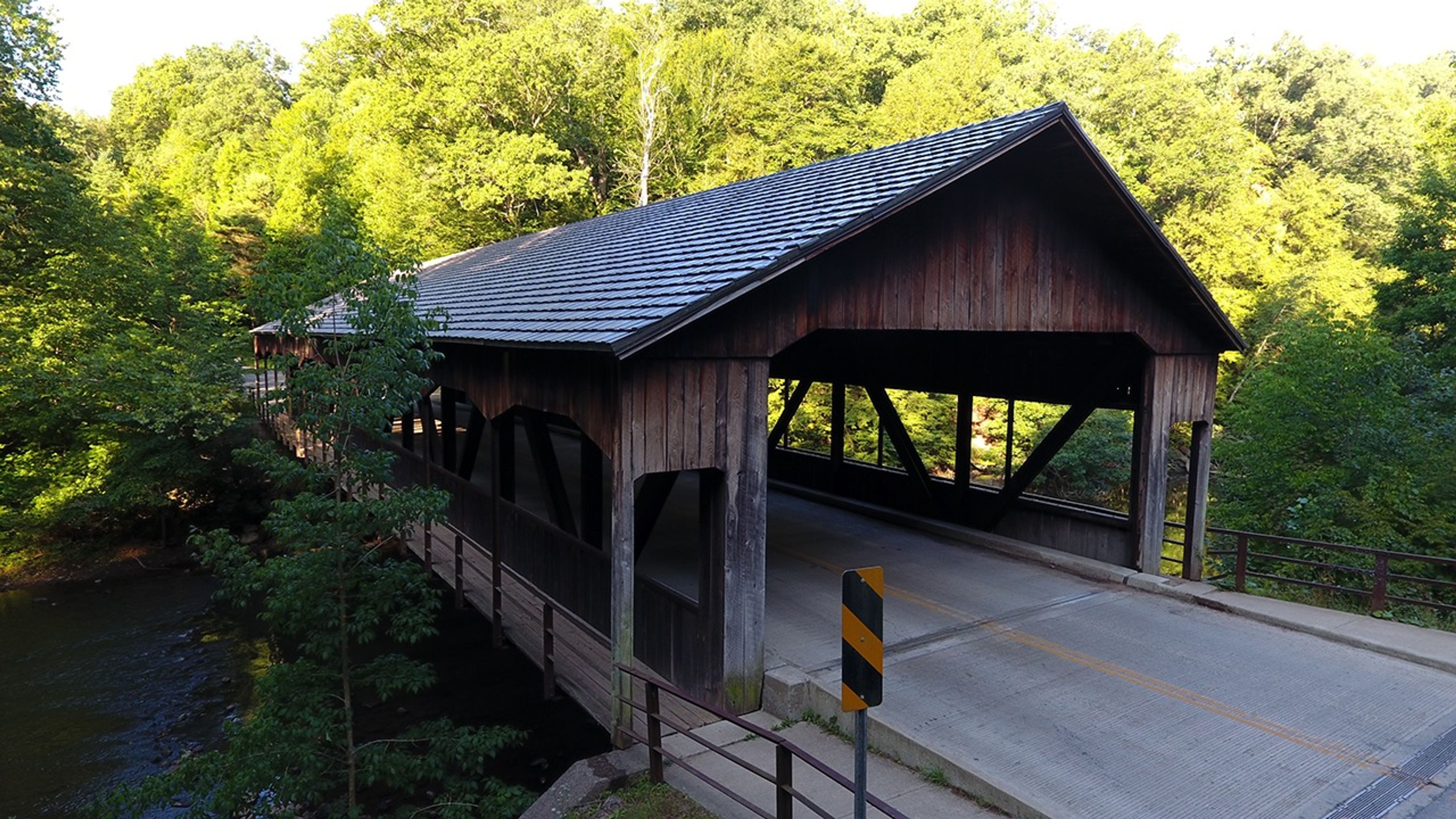 A covered bridge over a body of water with trees in the background at Mohican State Park