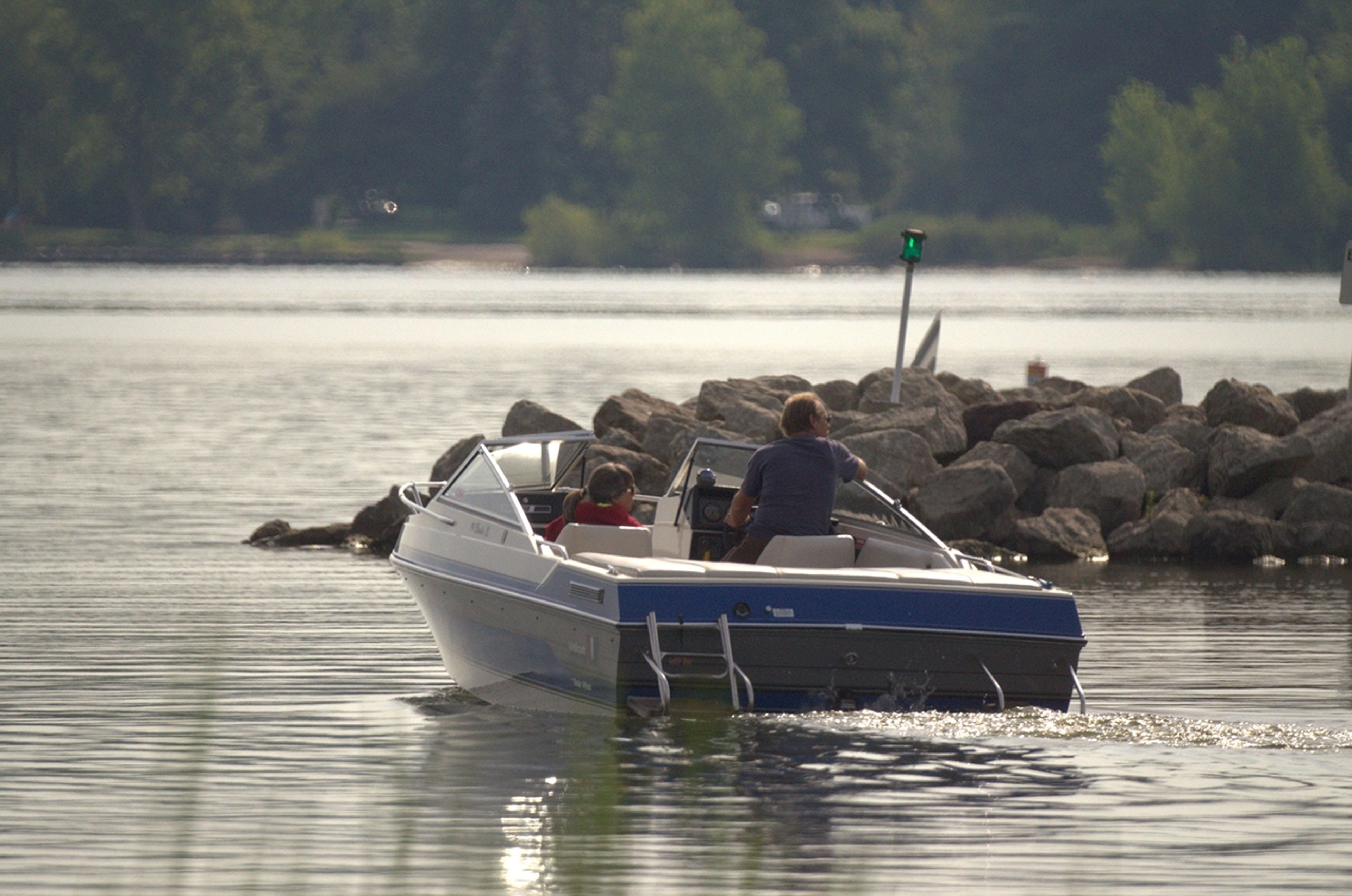 Two people in a speedboat on the water near a rocky shore at Mosquito Lake State Park