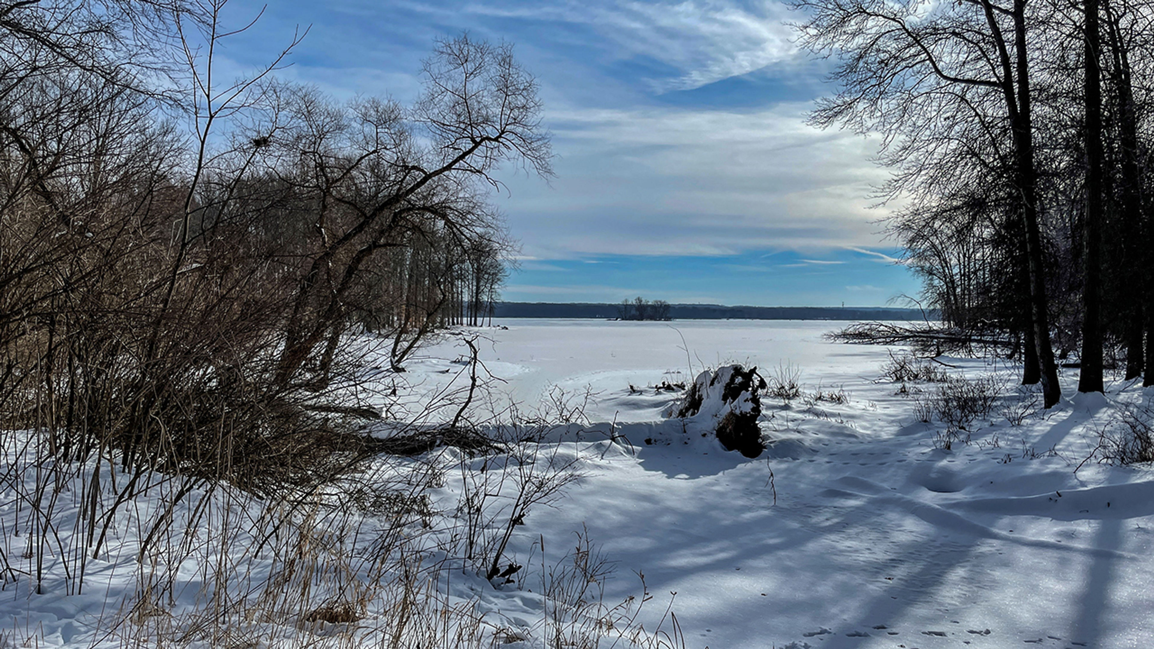 A snow covered lake with trees and blue sky at Mosquito Lake State Park