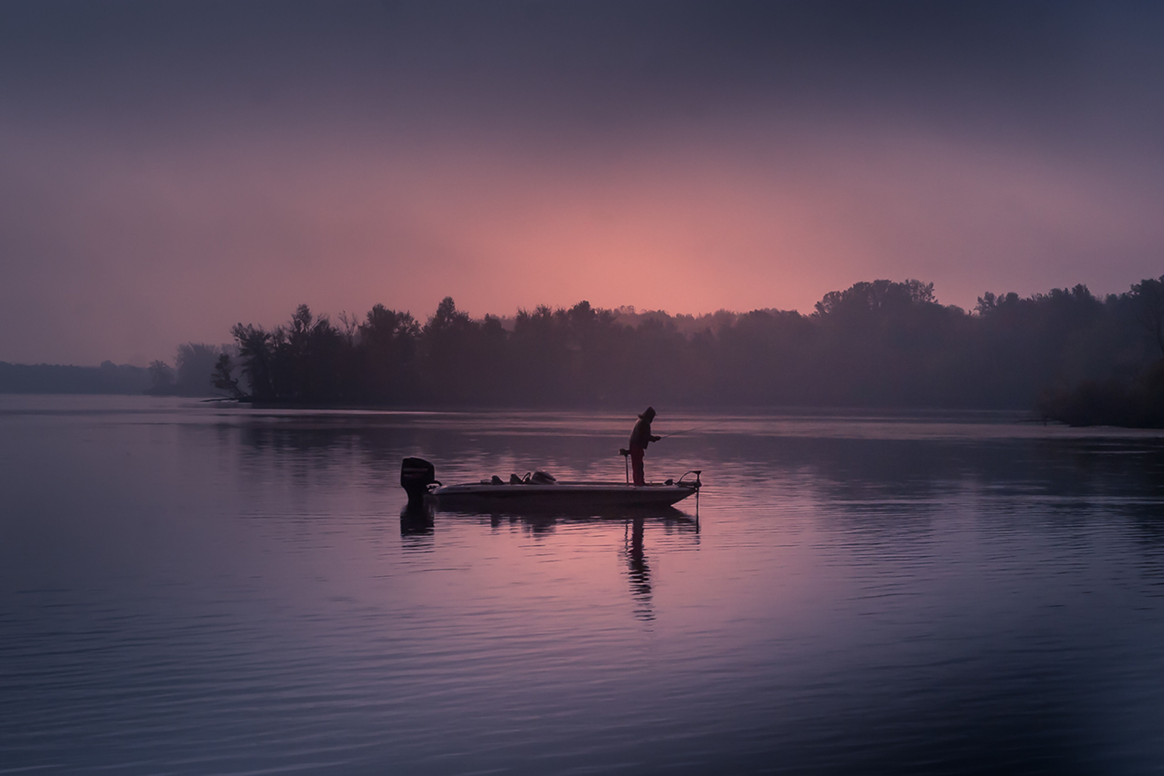 A person on a boat in the water at dusk at Mosquito Lake State Park