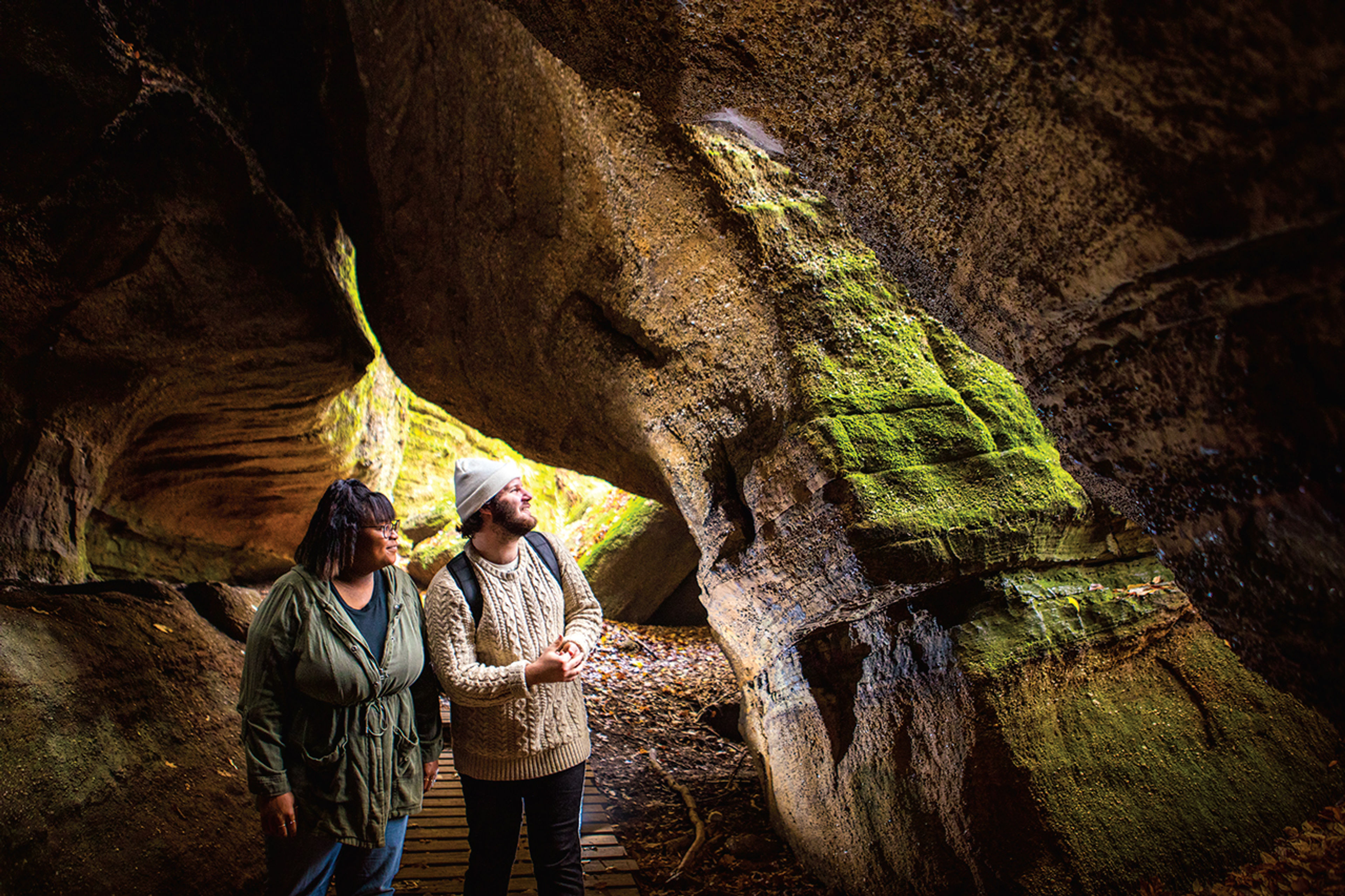 Two people walking though a rock formation at Nelson-Kennedy Ledges State Park