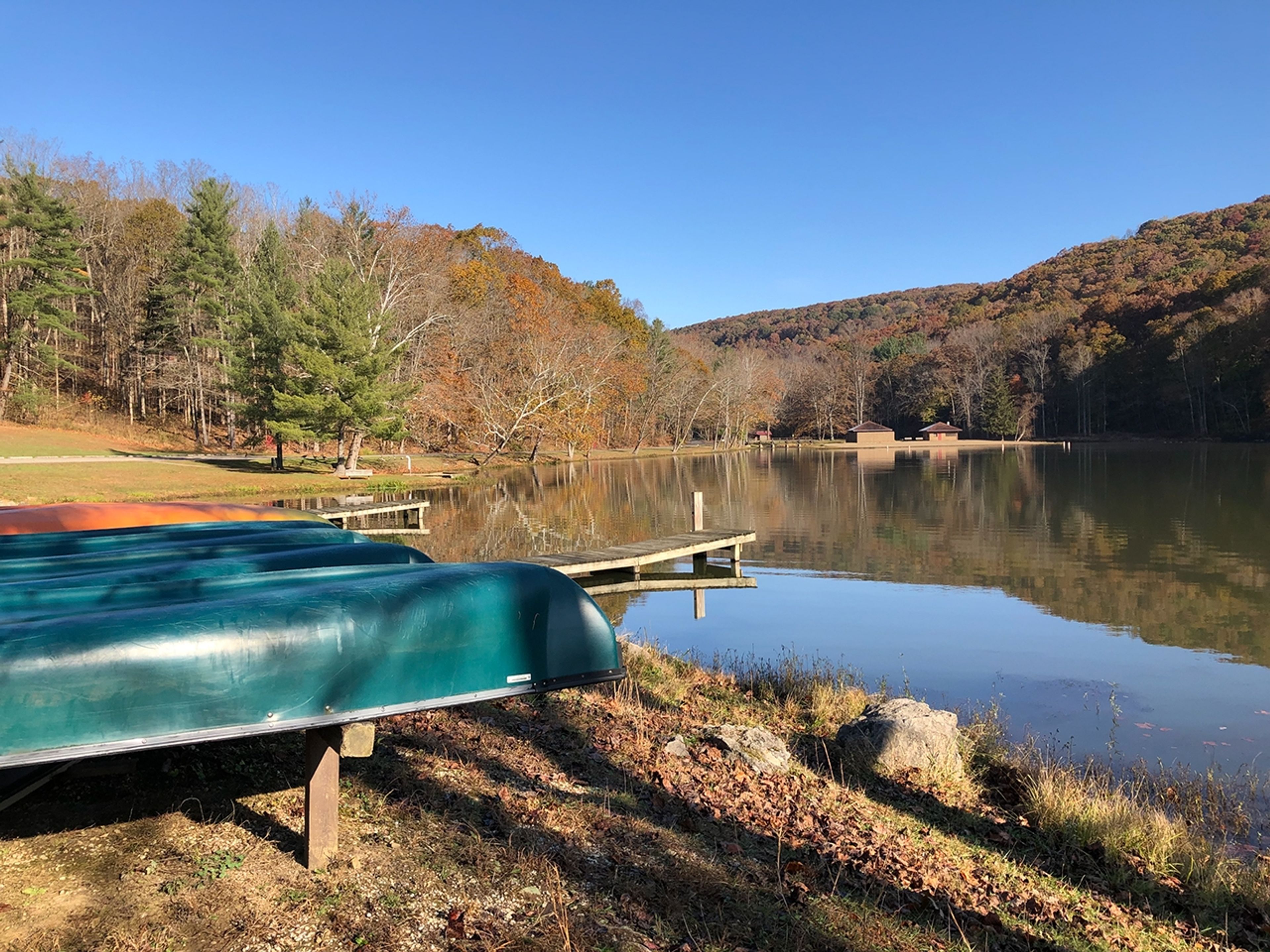 Row of canoes on the side of a lake near a wooden dock at Pike Lake State Park