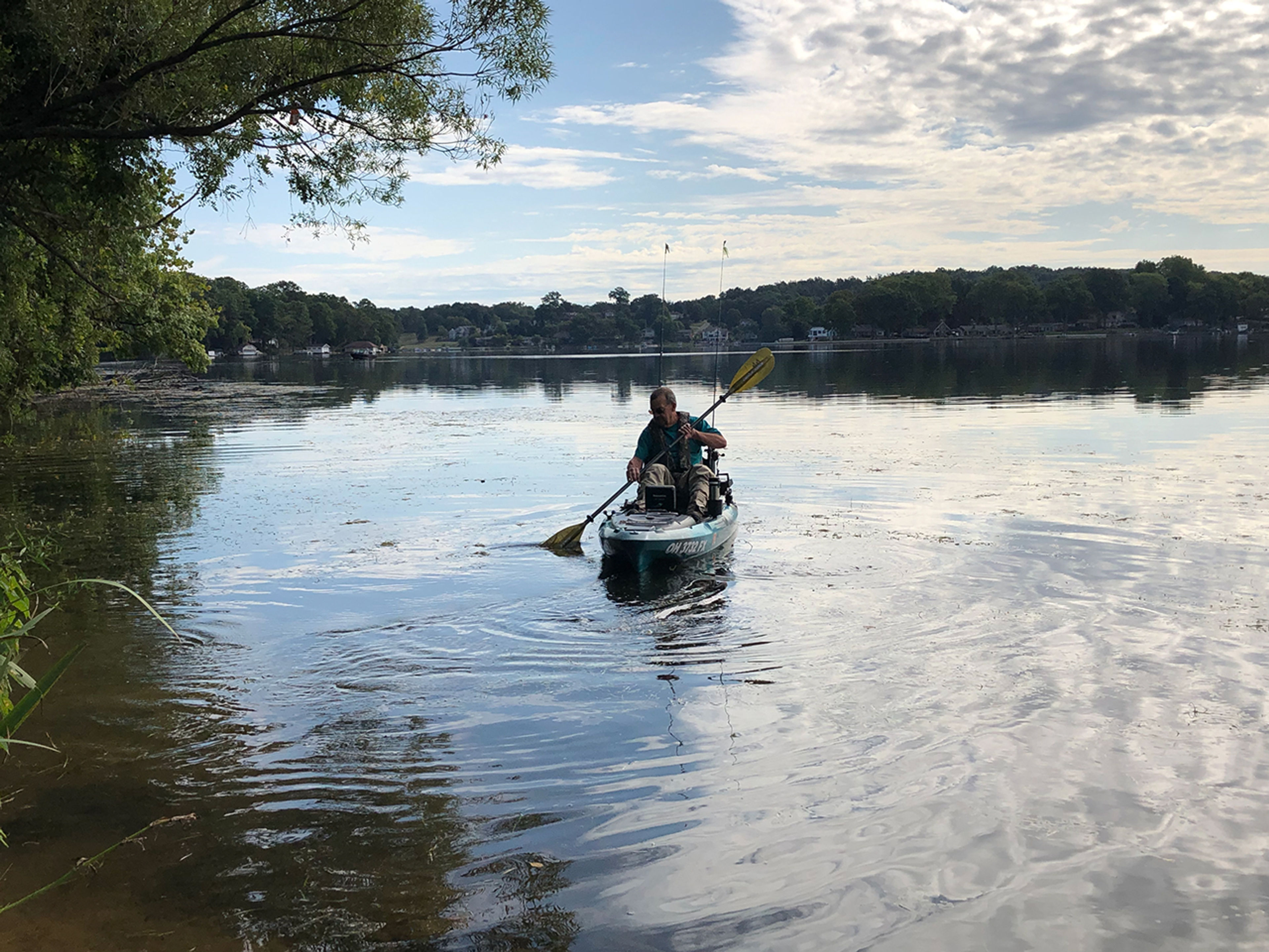 A person in a boat on the water with a paddle at Portage Lakes State Park